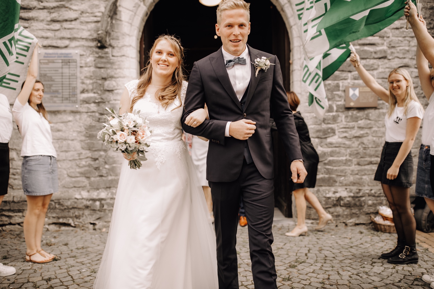 bruid en bruidegom wandelen de kerk uit na huwelijksviering te belsele