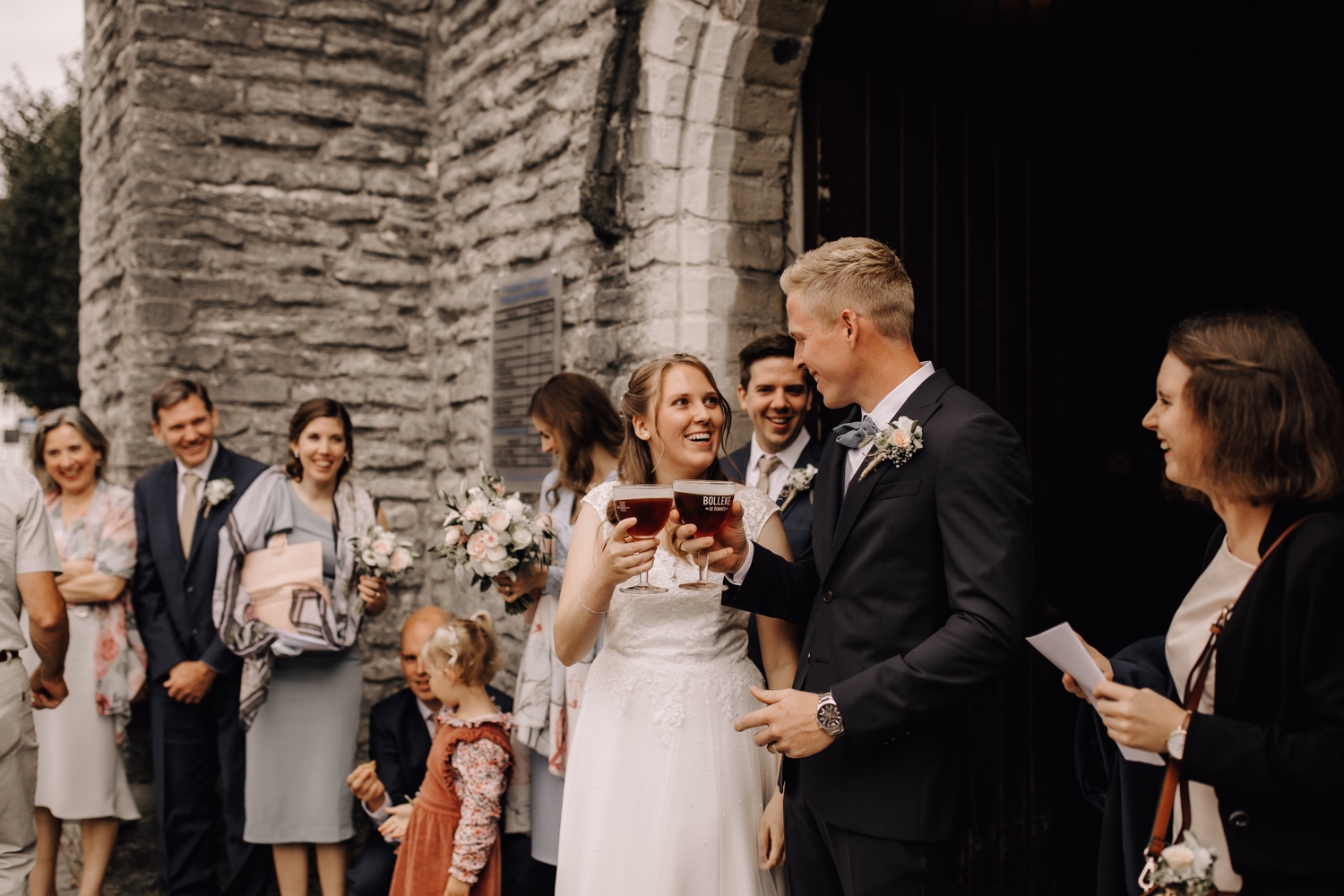 bruid en bruidegom klinken een biertje aan de kerk te belsele