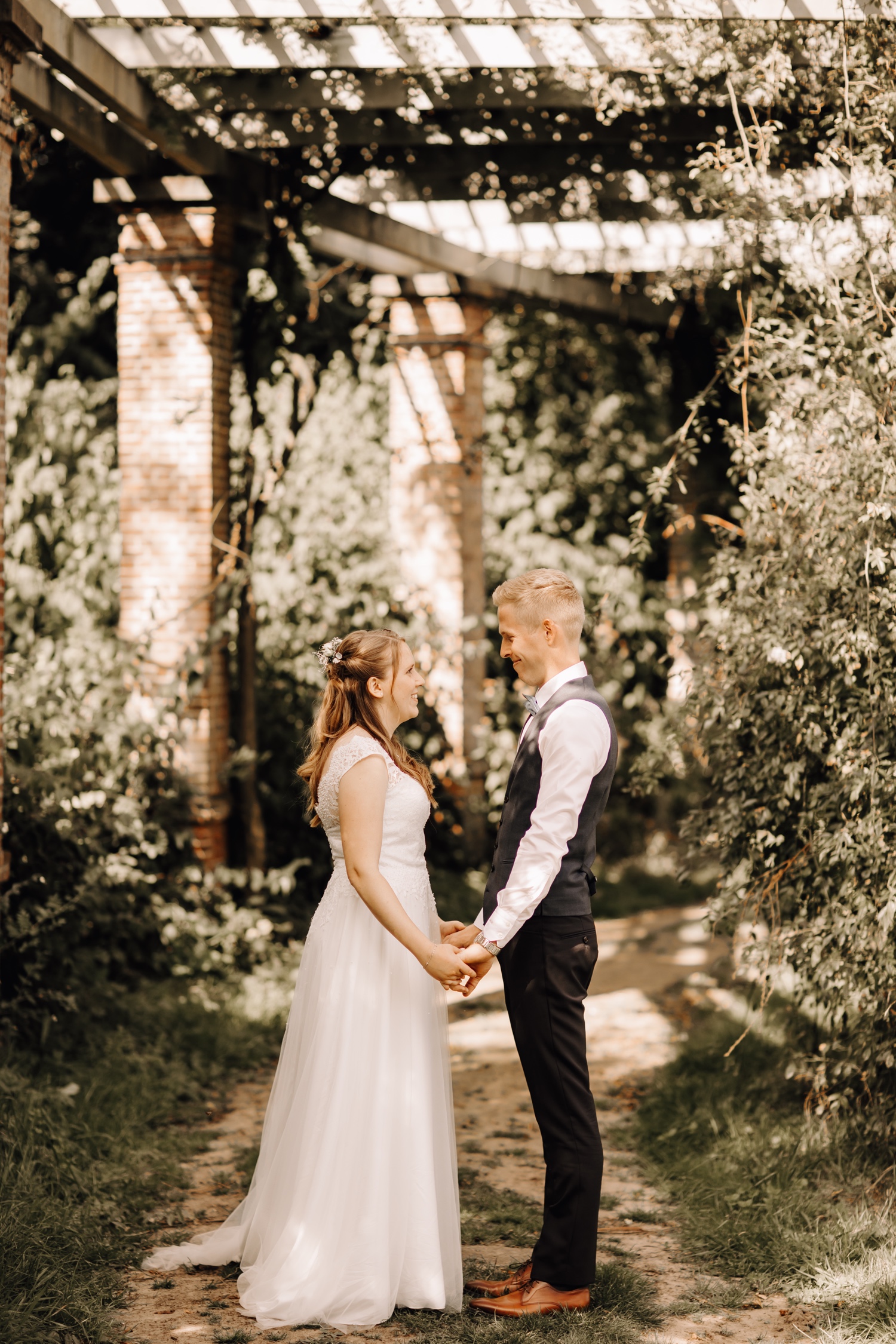 Bruid en bruidegom kijken naar elkaar tijdens fotoshoot in park van beervelde