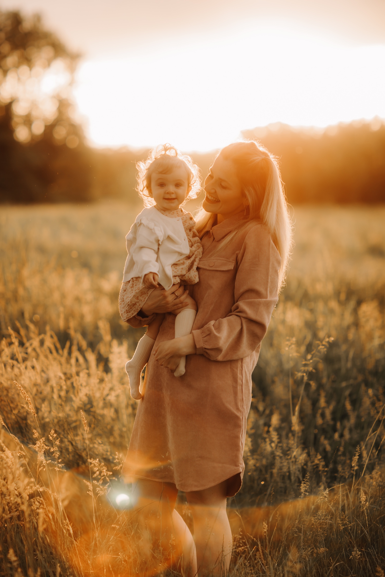 moeder poseert met dochter in veldje tijdens zonsondergang te Beverlo