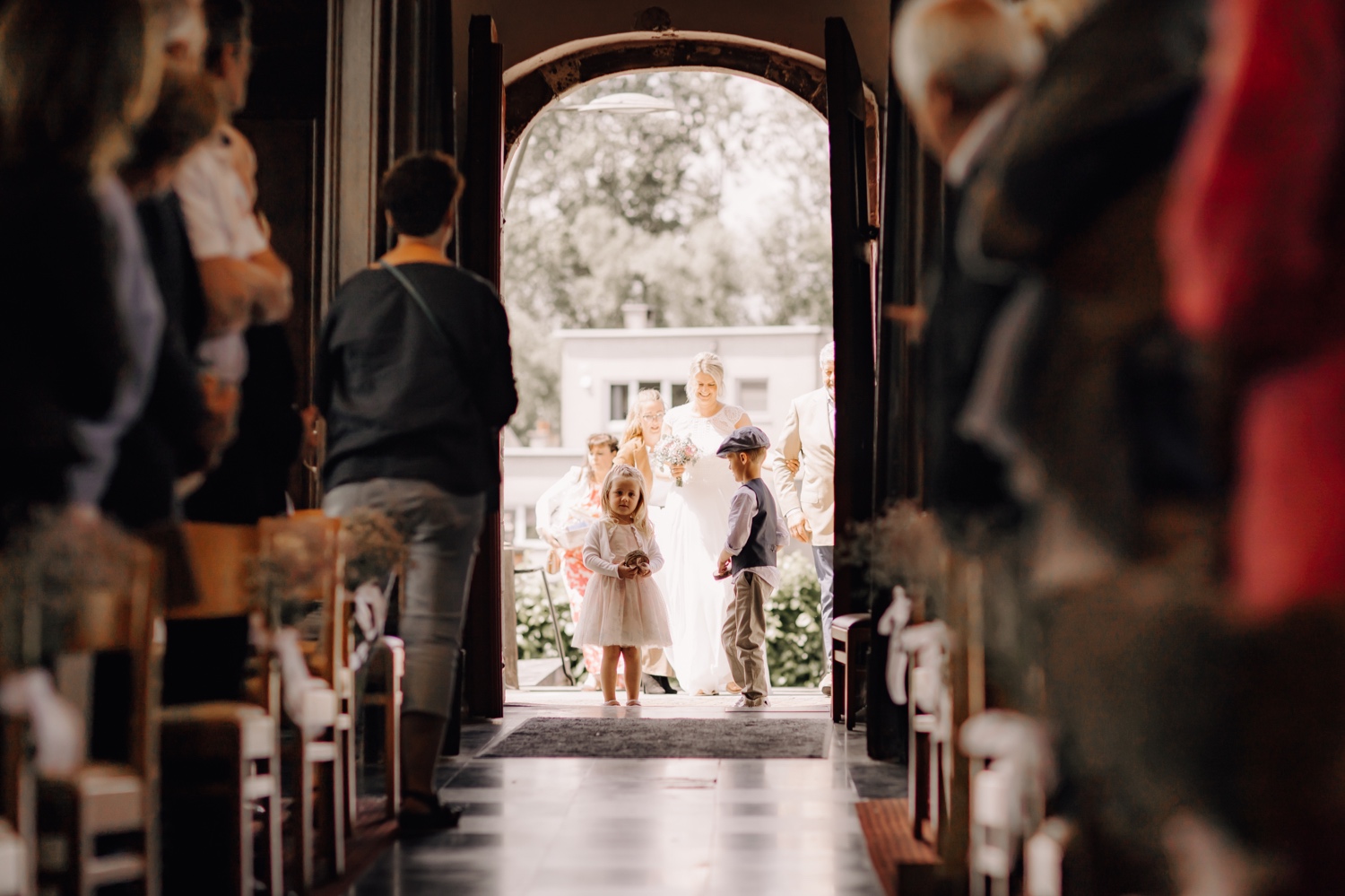 nichtje en zoon van bruid en bruidegom wandelen de kerk binnen als bruidskindjes