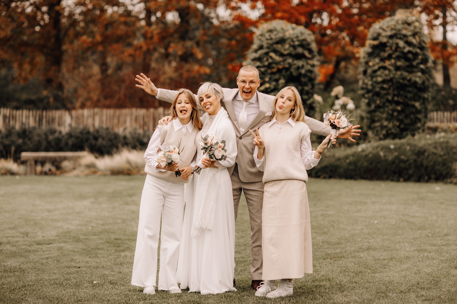 Bruid en bruidegom poseren met hun dochters in eigen tuin
