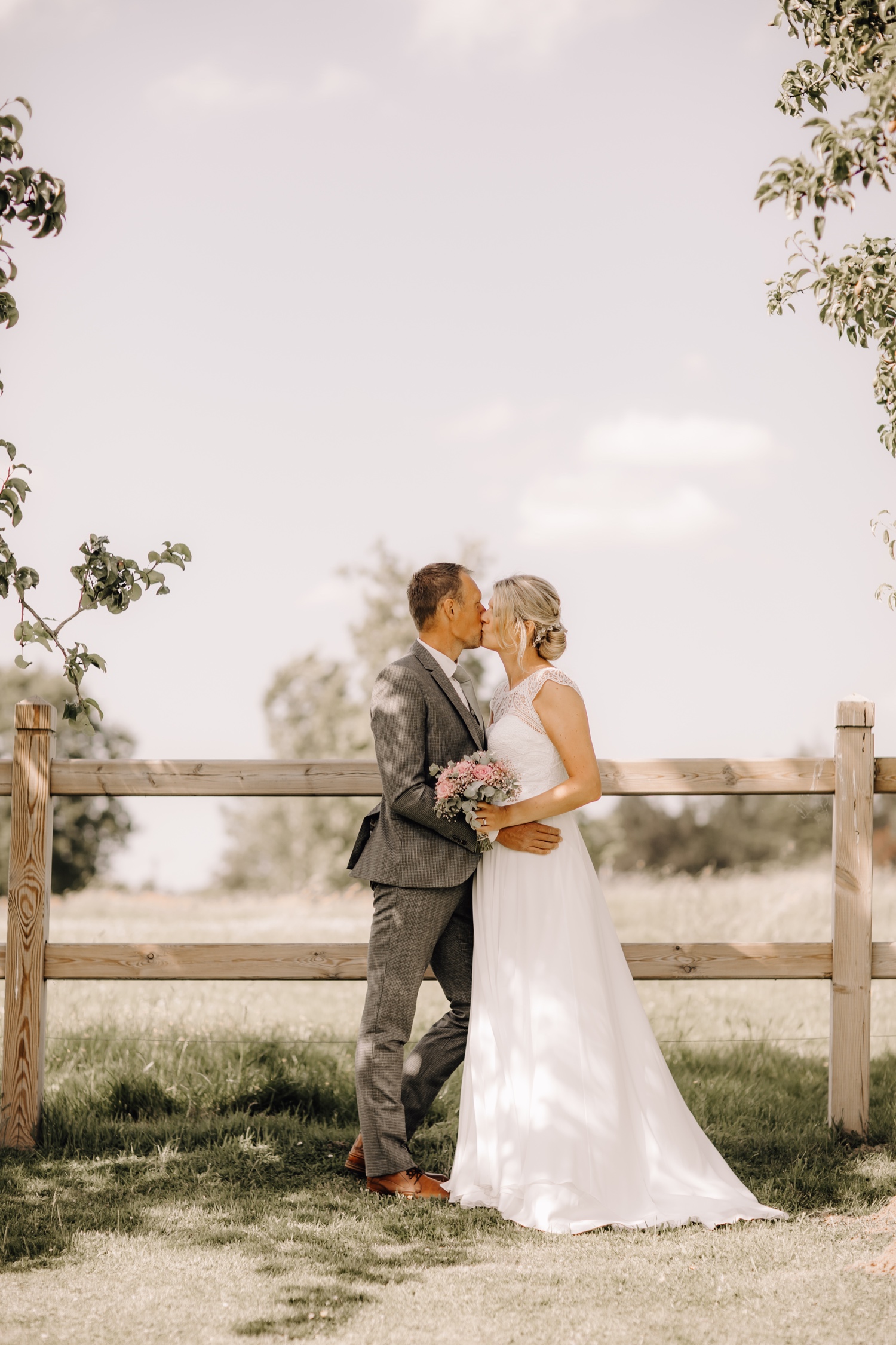 Bruidspaar deelt innige kus tijdens fotoshoot in de tuin van feestzaal Hof ten Eenhoorn te Asse