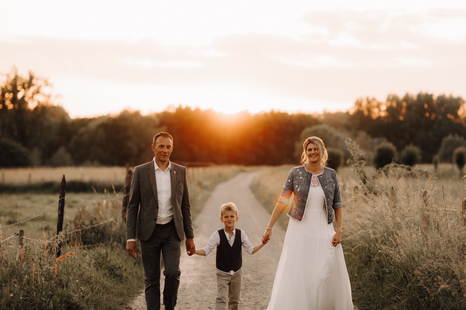 Bruid en bruidegom wandelen samen met hun zoontje tijdens fotoshoot te Asse