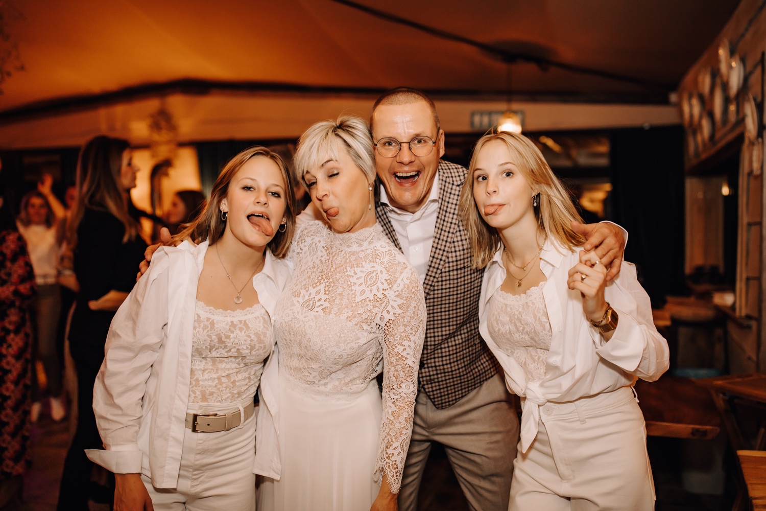 Bruid en bruidegom trekken een gek gezicht met hun dochters als afsluiter van hun feest