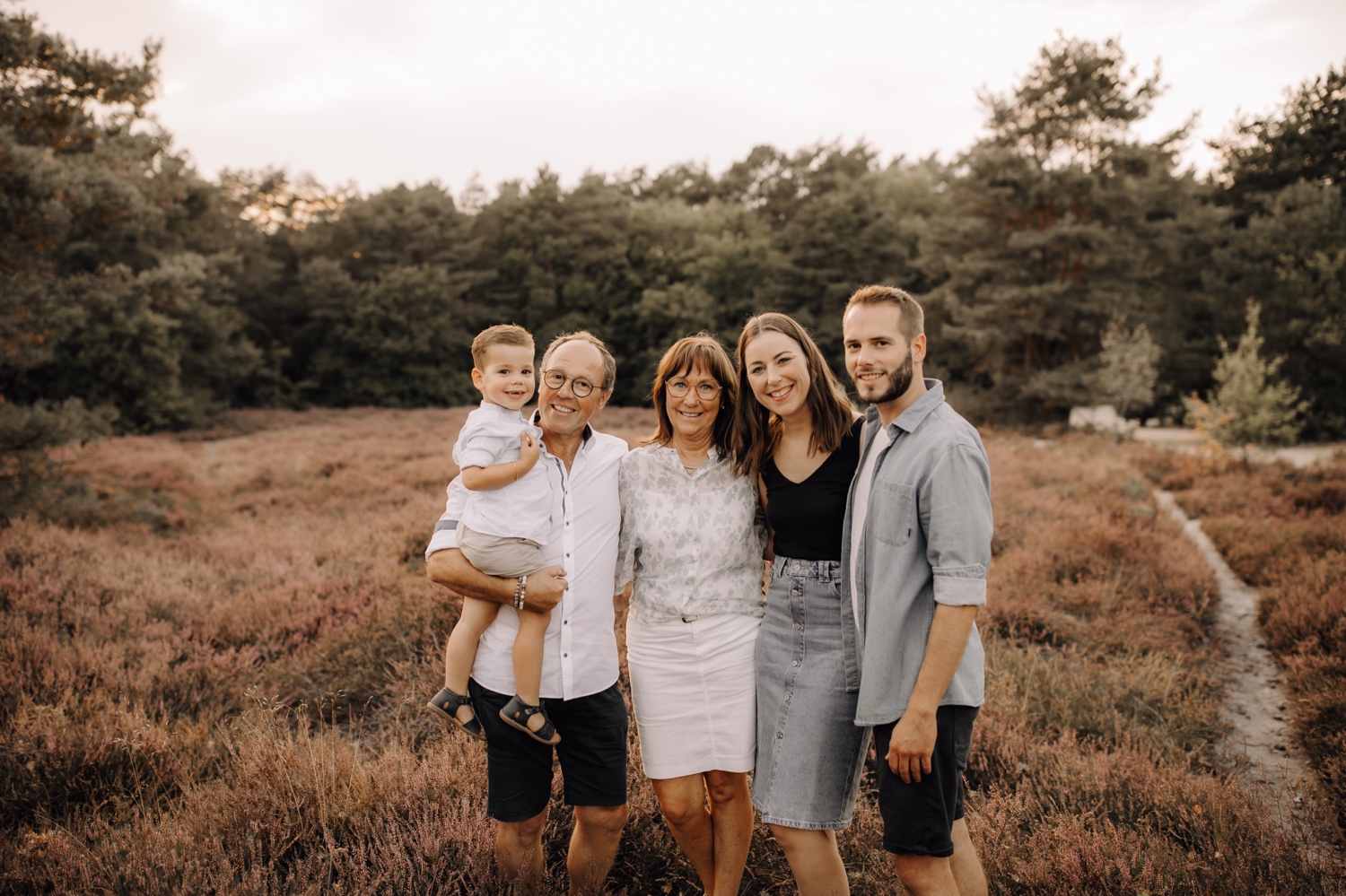 gezinsfotograaf Limburg - familie knuffelt elkaar stevig in de heide van Zonhoven