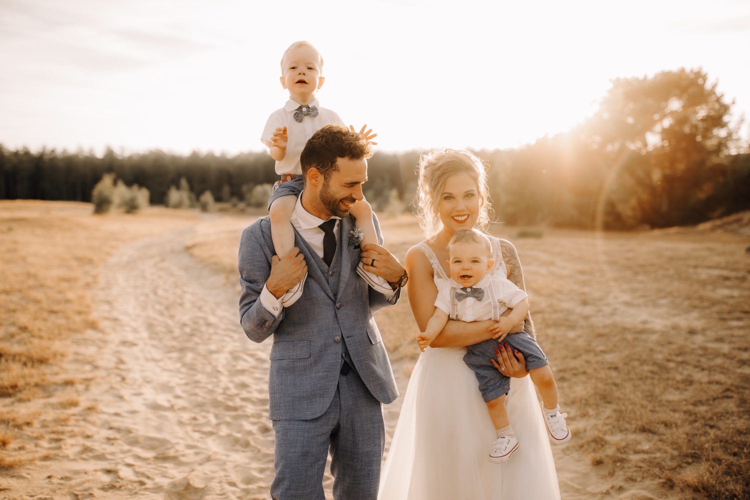 Huwelijksfotograaf Limburg - gezinsportret van bruidspaar met kinderen bij zonsondergang