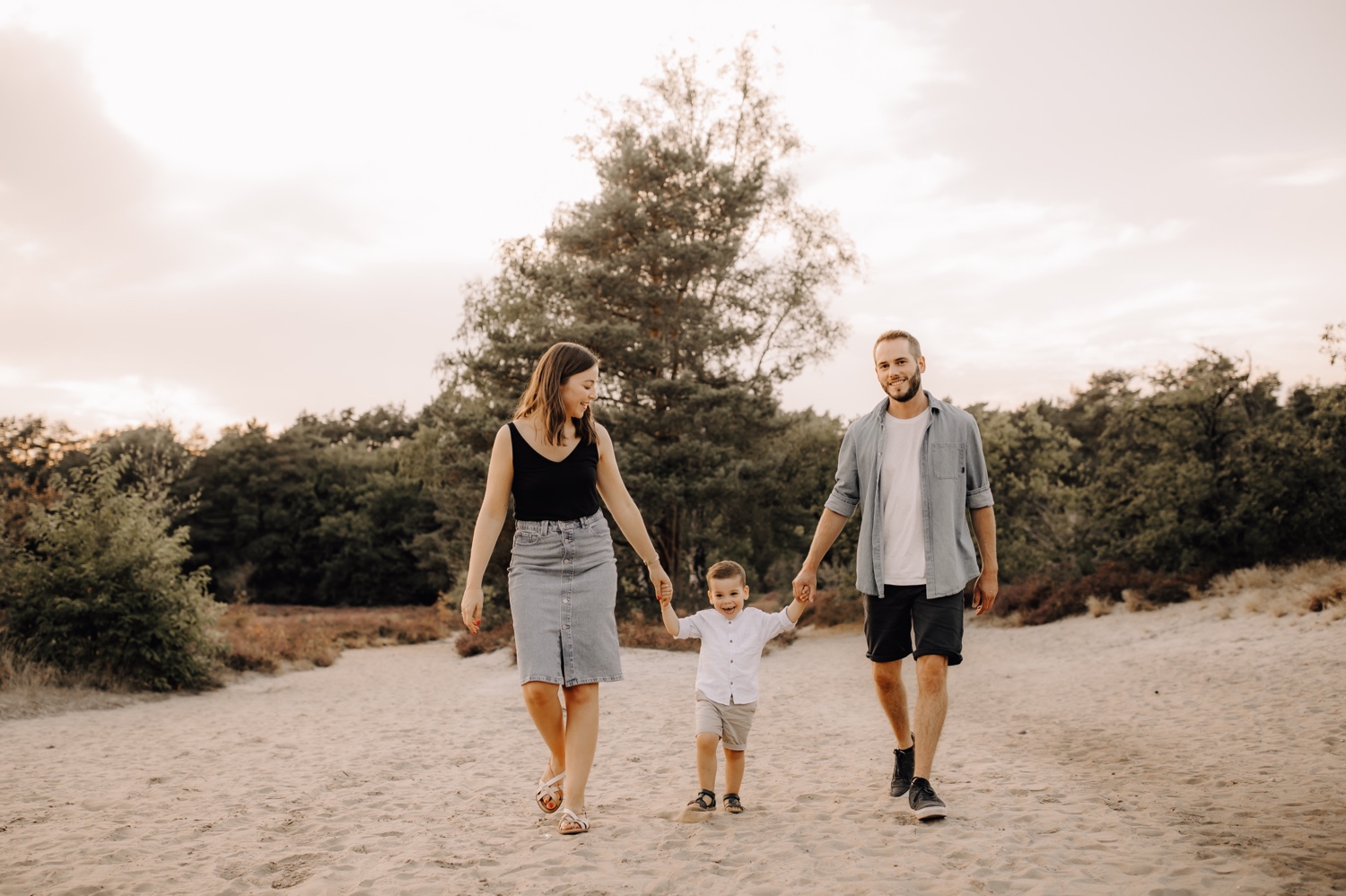 gezinsfotograaf Limburg - gezin wandelt met zoontje door het zand