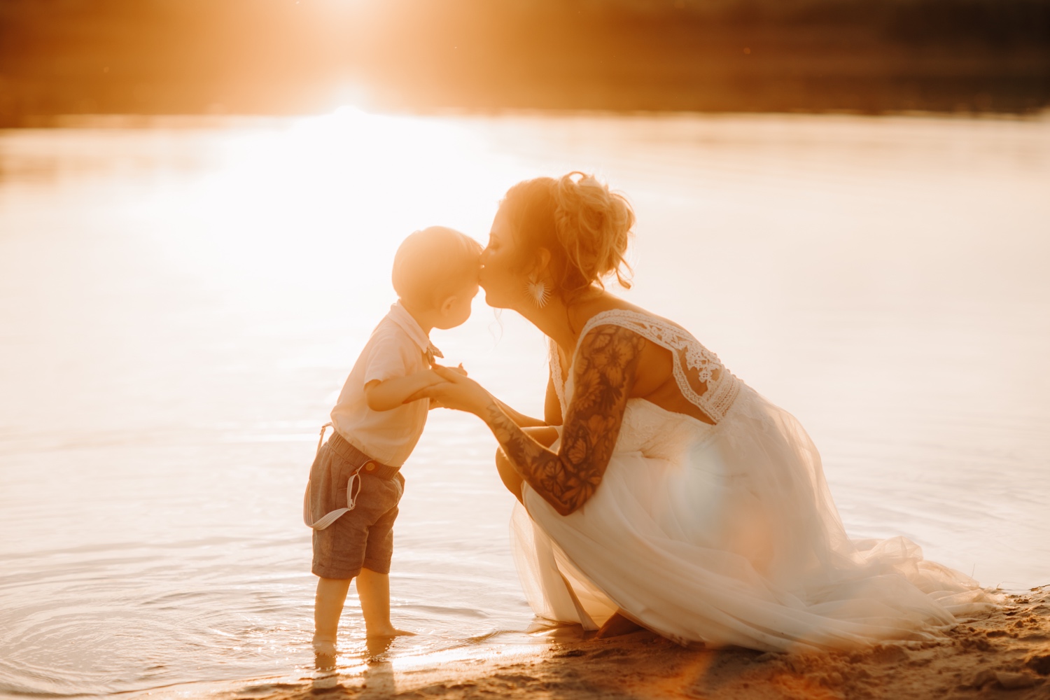 Huwelijksfotograaf Limburg - Bruid kust haar zoontje op zijn voorhoofd tijdens zonsondergang