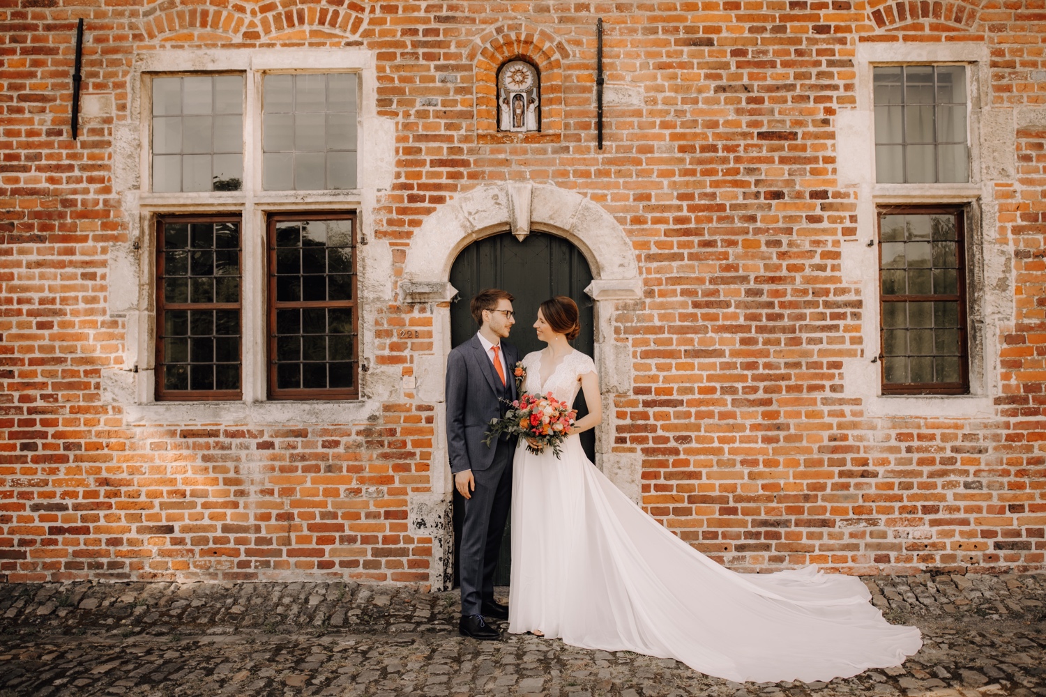 Huwelijksfotograaf Limburg - bruidspaar poseert voor deur van voormalig studentenkot in begijnhof