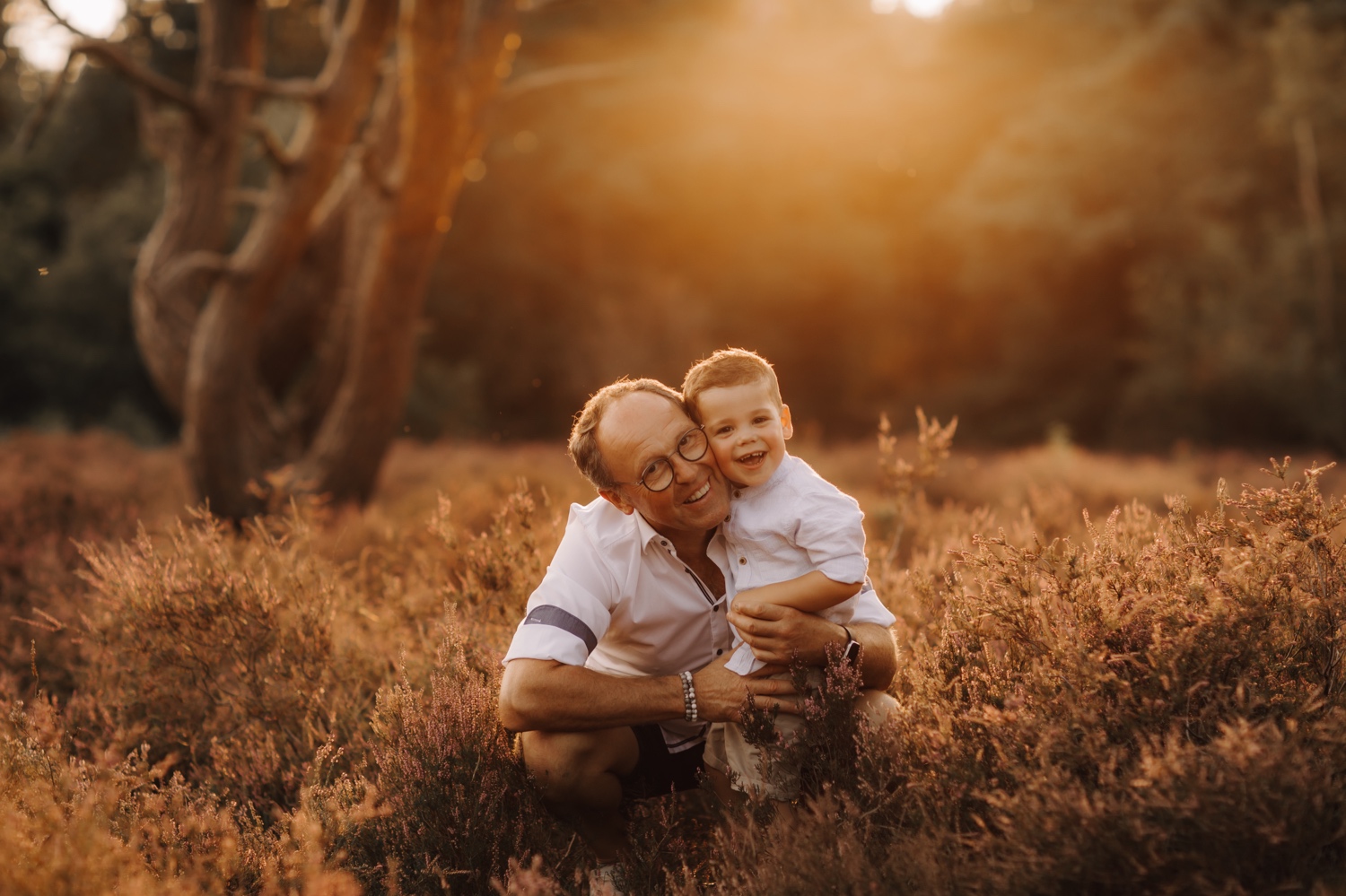 gezinsfotograaf Limburg - grootvader en kleinzoon knuffelen tijdens zonsondergang in de teut te Zonhoven