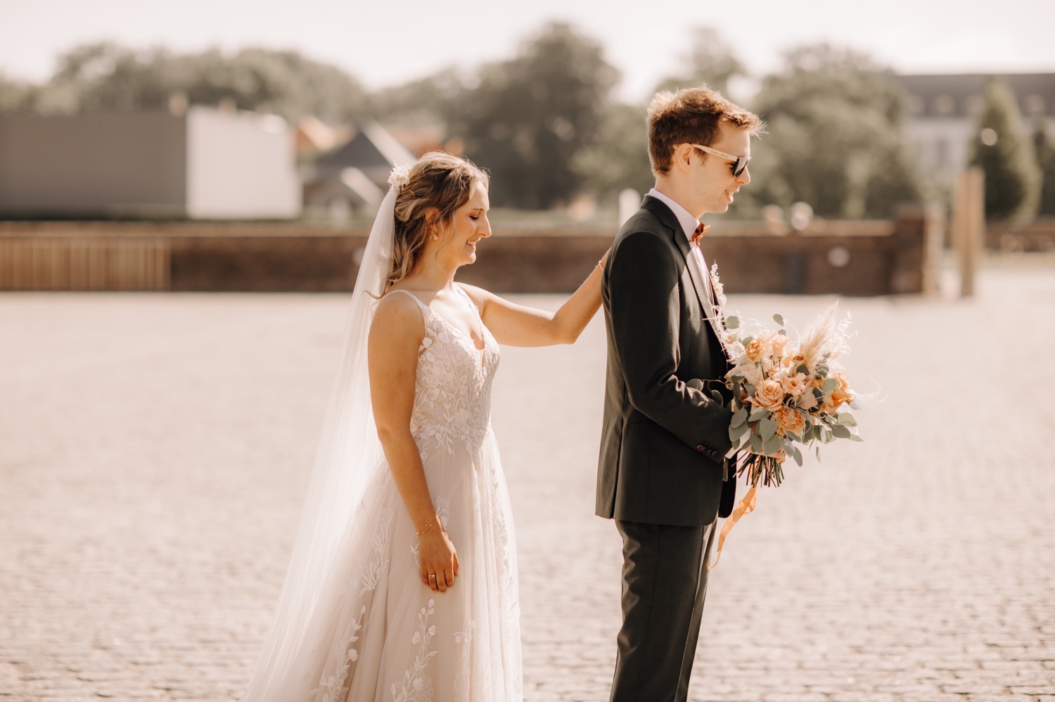 Huwelijksfotograaf Limburg - bruid legt haar hand op zijn schouder bij first look