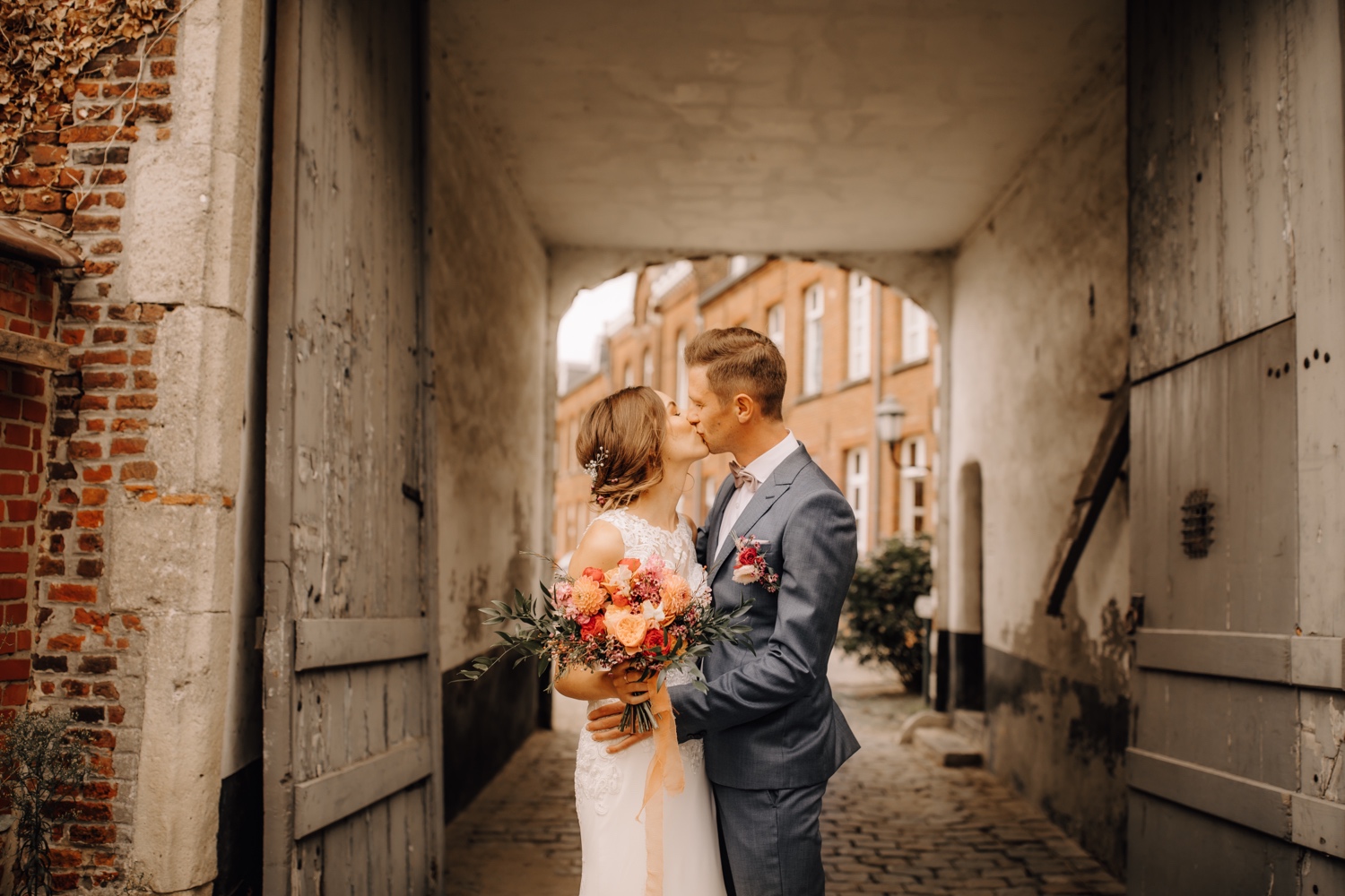 Huwelijksfotograaf limburg - bruid en bruidegom kussen onder de brug van het begijnhof