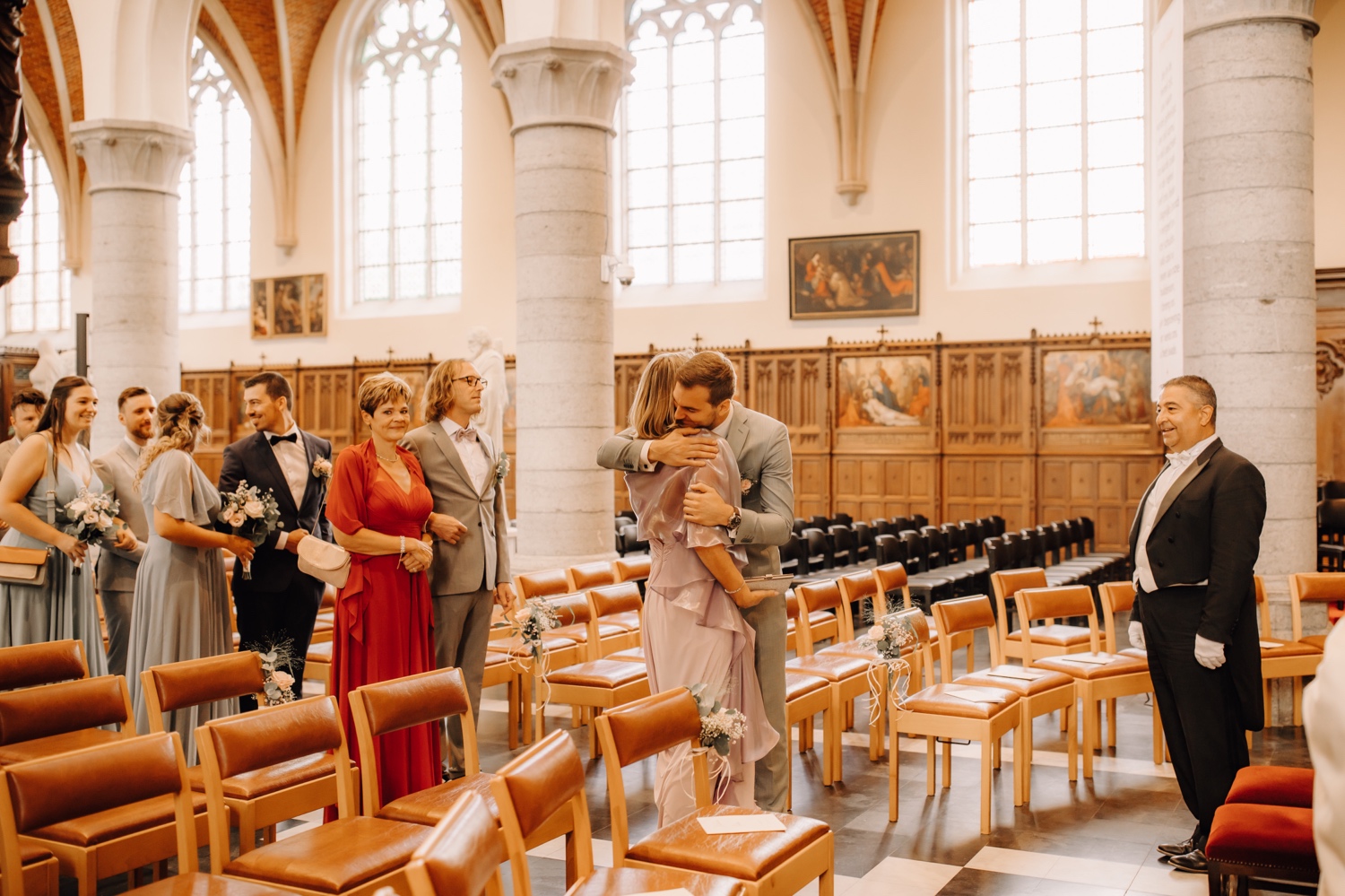 Huwelijksfotograaf Limburg - bruidegom geeft zijn moeder een knuffel in de kerk