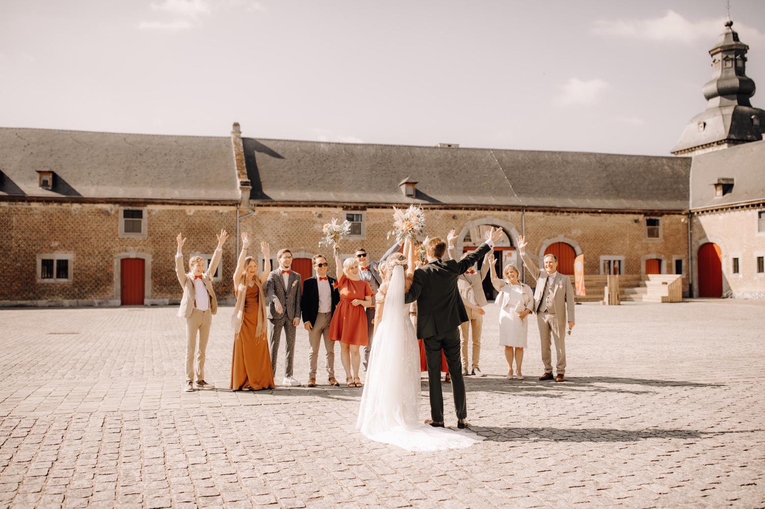 Huwelijksfotograaf Limburg - suite en bruidspaar steken handen in de lucht
