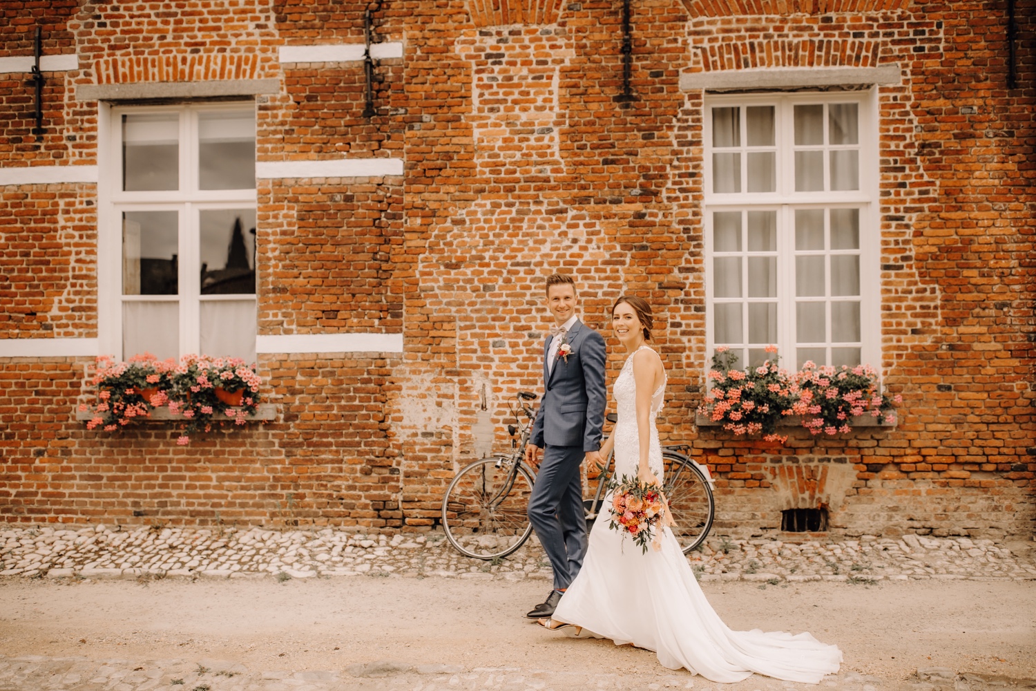 Huwelijksfotograaf limburg - bruidspaar wandelt door het begijnhof hand in hand