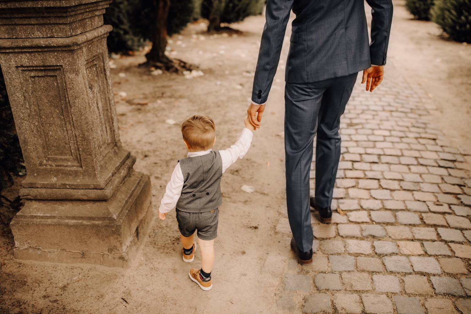 Huwelijksfotograaf limburg - bruidegom wandelt met zoontje door begijnhof