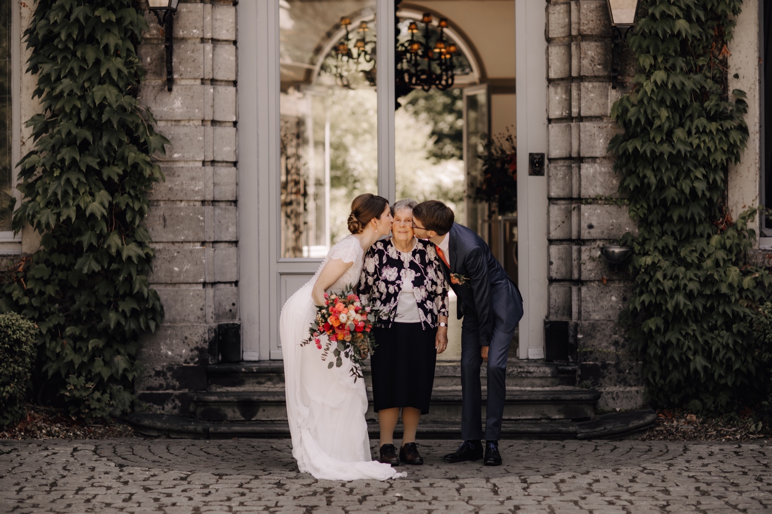 Huwelijksfotograaf Limburg - bruidspaar kust oma op wang