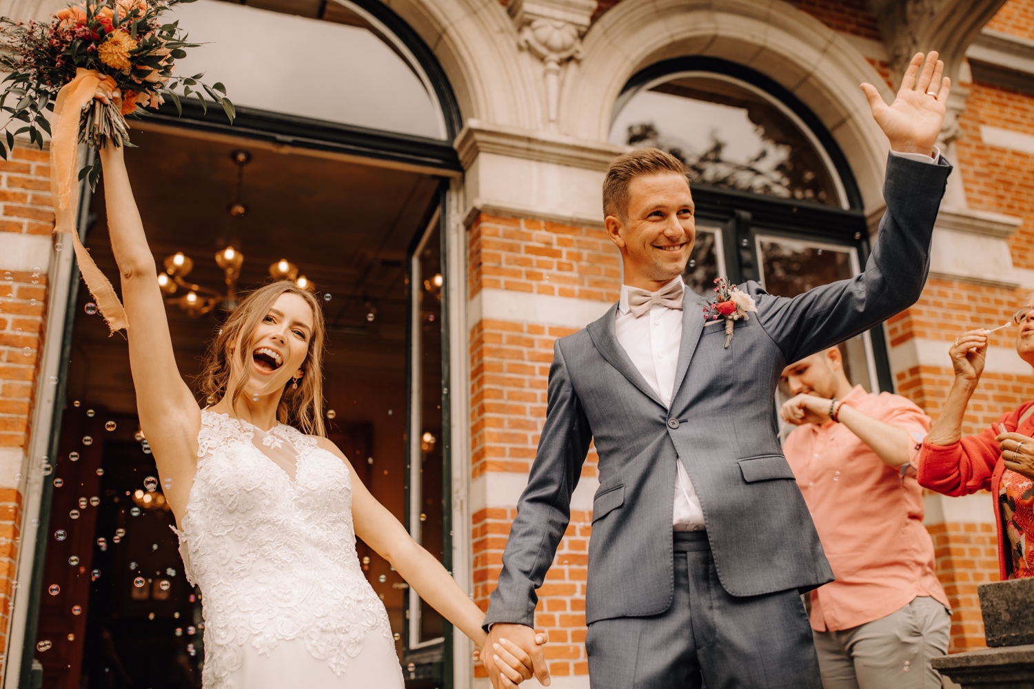 Huwelijksfotograaf limburg - bruidspaar steekt armen in de lucht