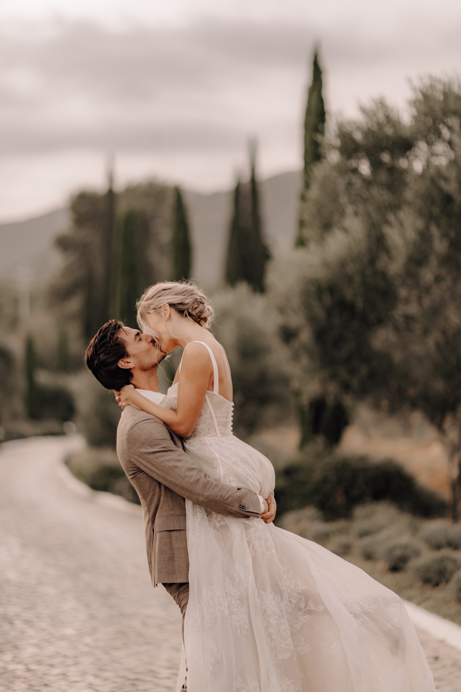 Huwelijksfotograaf buitenland - bruidegom heft zijn bruid op tussen de cipressen in Portugal