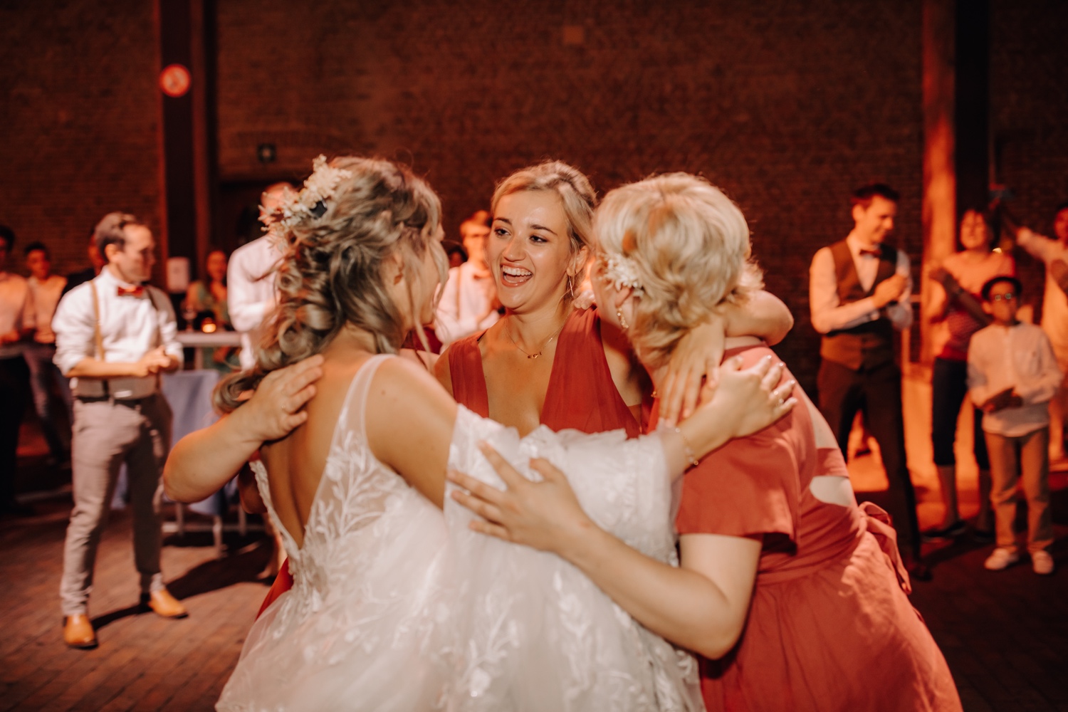 Huwelijksfotograaf Limburg - bruidsmeisjes knuffelen elkaar op de dansvloer