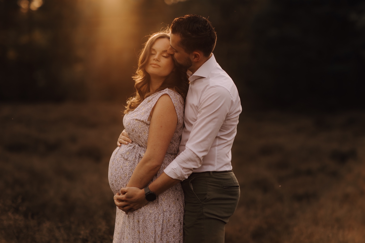 gezinsfotograaf Limburg - zwanger koppelt knuffelt elkaar innig bij zonsondergang in de Teut