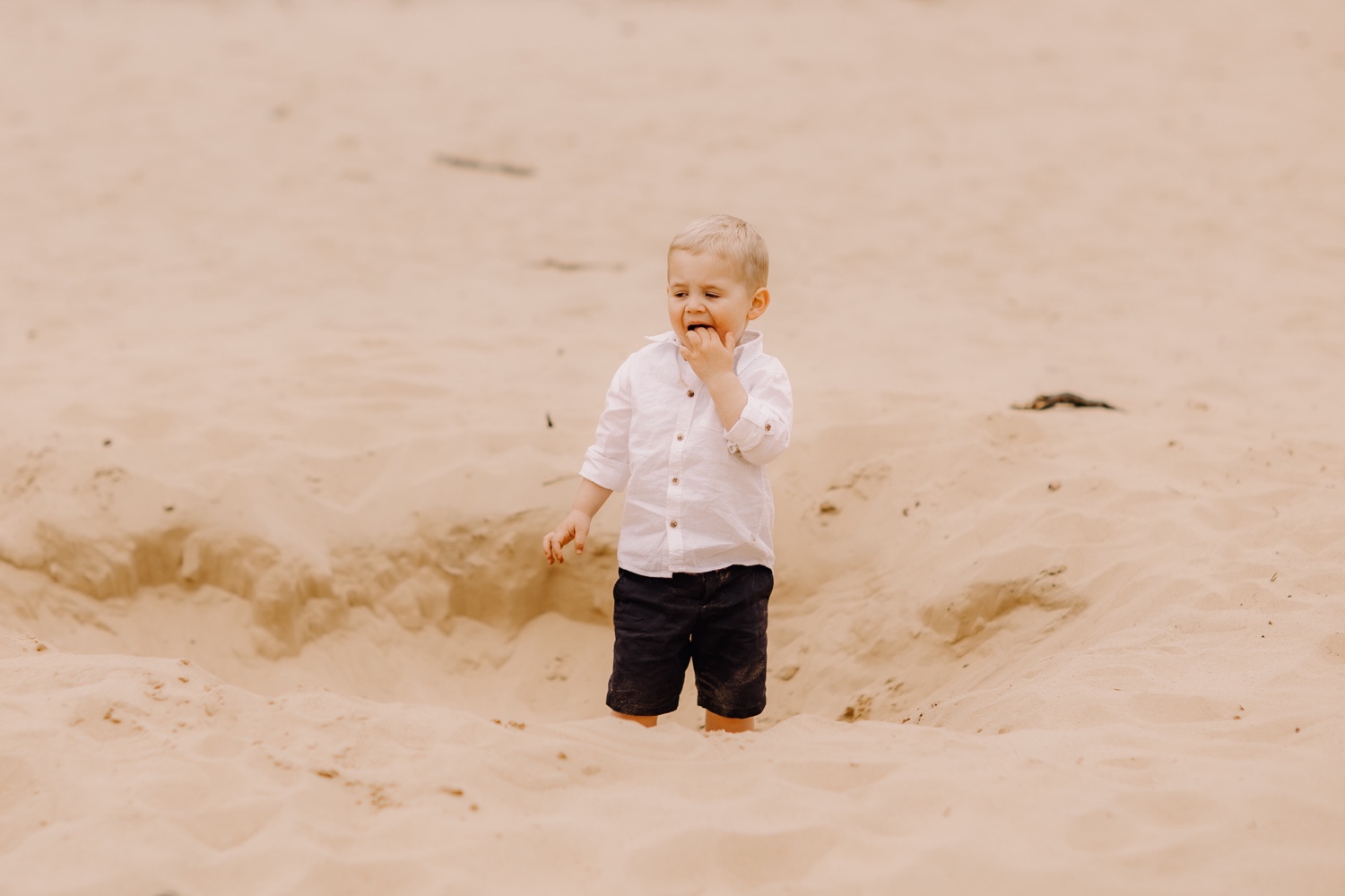 gezinsfotograaf Limburg - kleinzoon eet zand tijdens fotoshoot