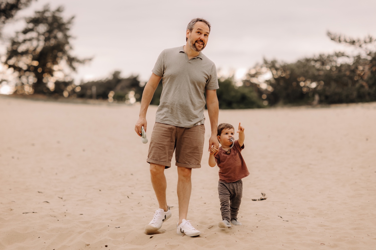 gezinsfotograaf Limburg - vader wandelt met zoontje door het zand in Hechtel