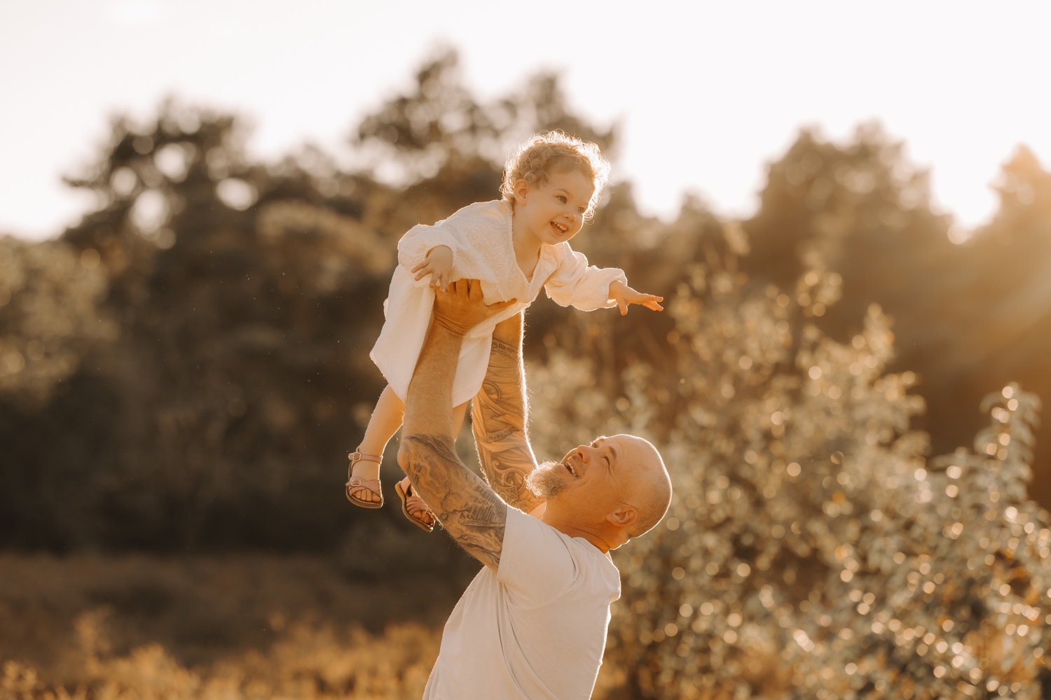 papa zwiert dochtertje in de lucht tijdens fotosessie