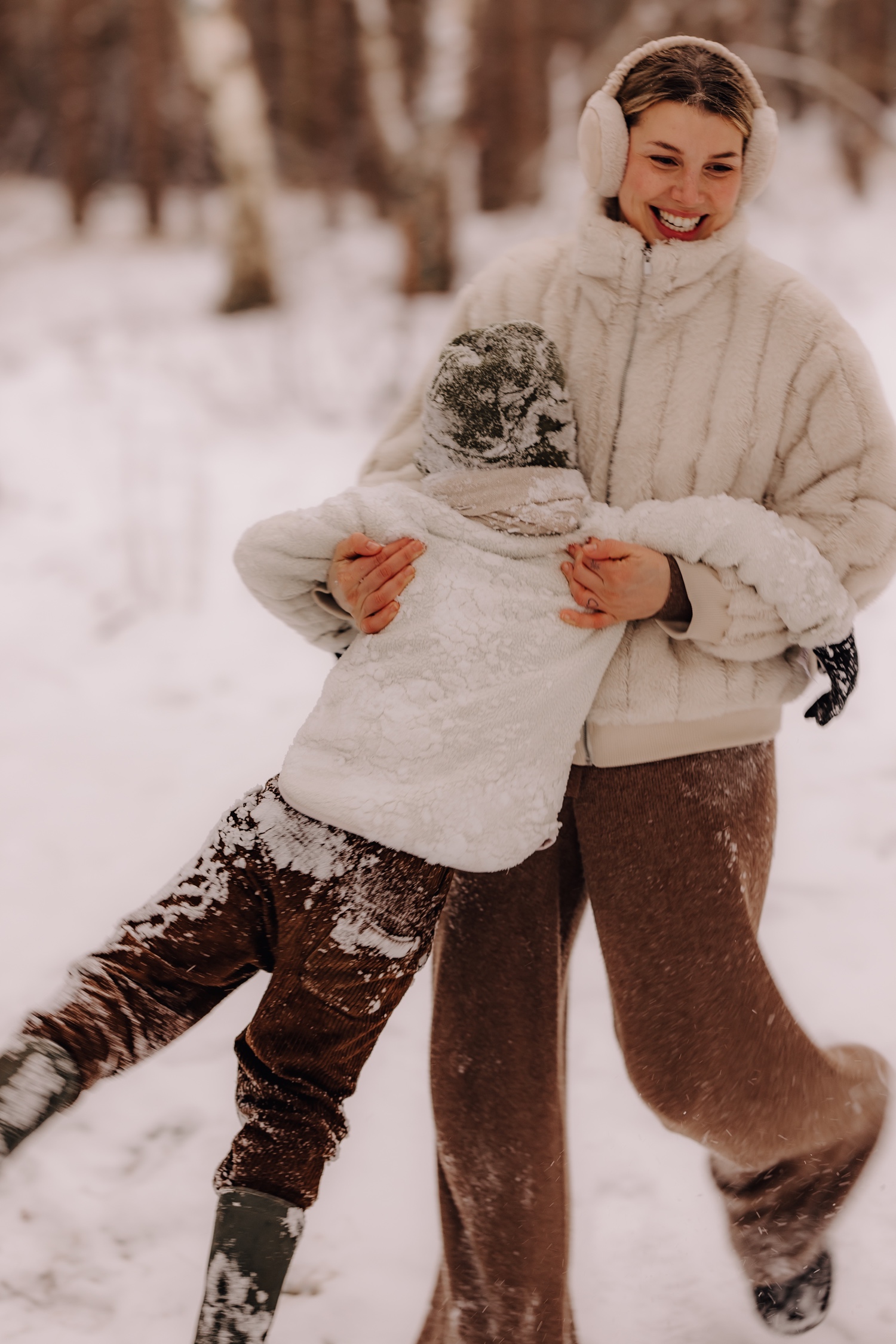 moeder zwiert haar zoontje rond in de sneeuw