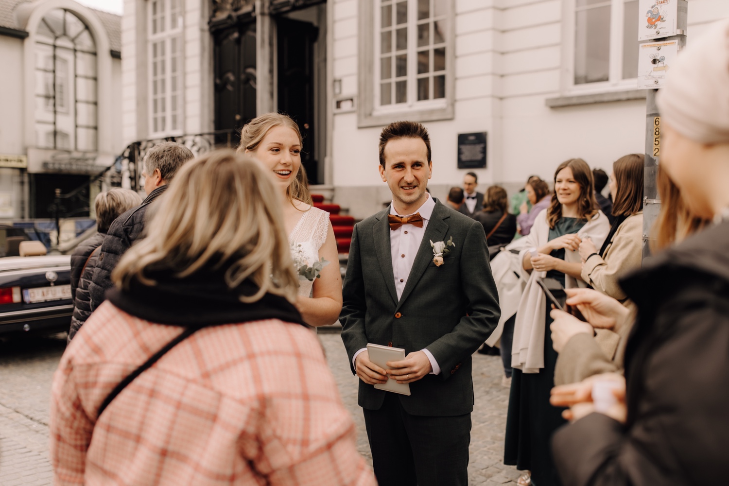 Huwelijksfotograaf Limburg - bruidspaar groet gasten aan het gemeentehuis