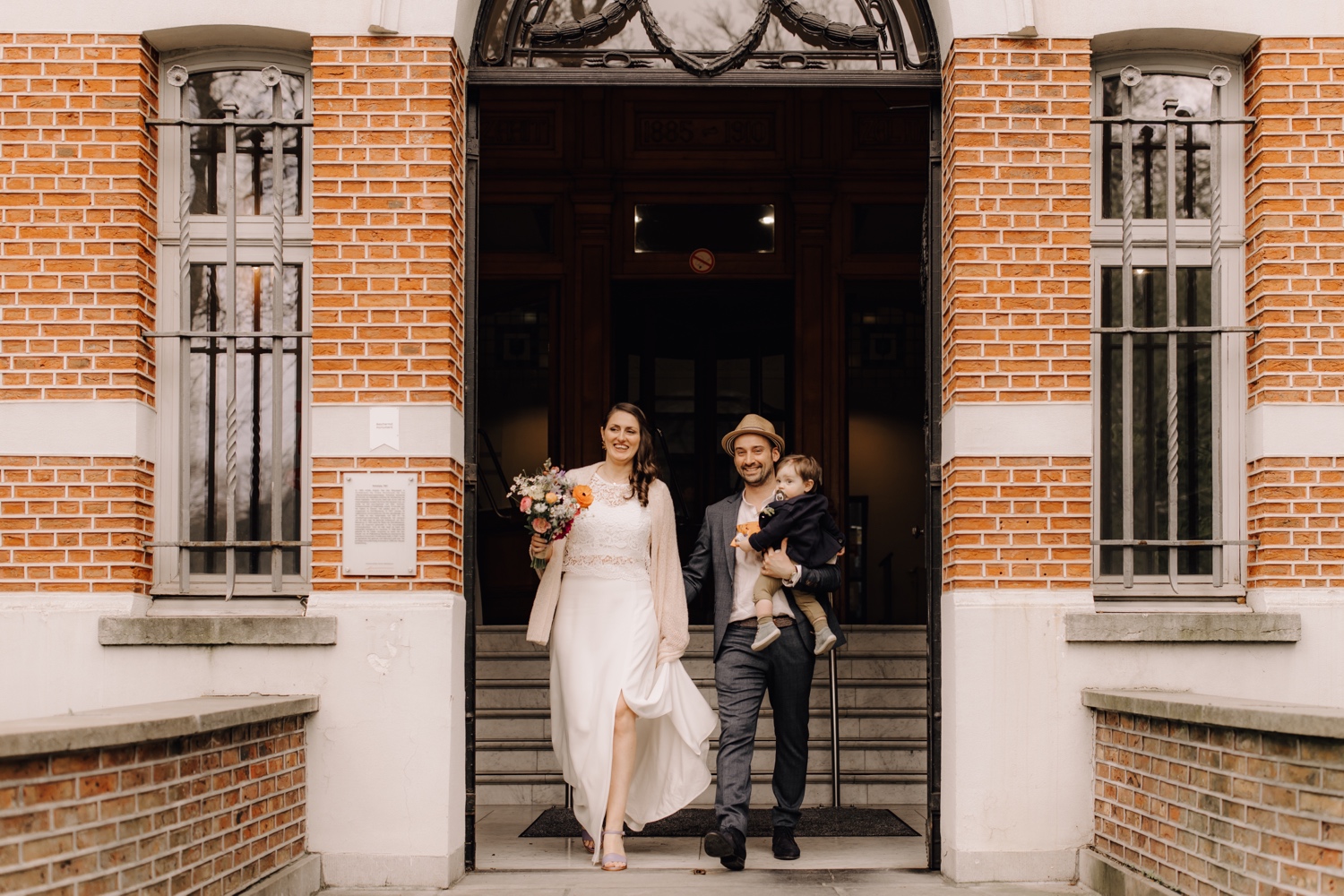 Huwelijksfotograaf Limburg - bruidspaar wandelt stadhuis uit samen met zoontje