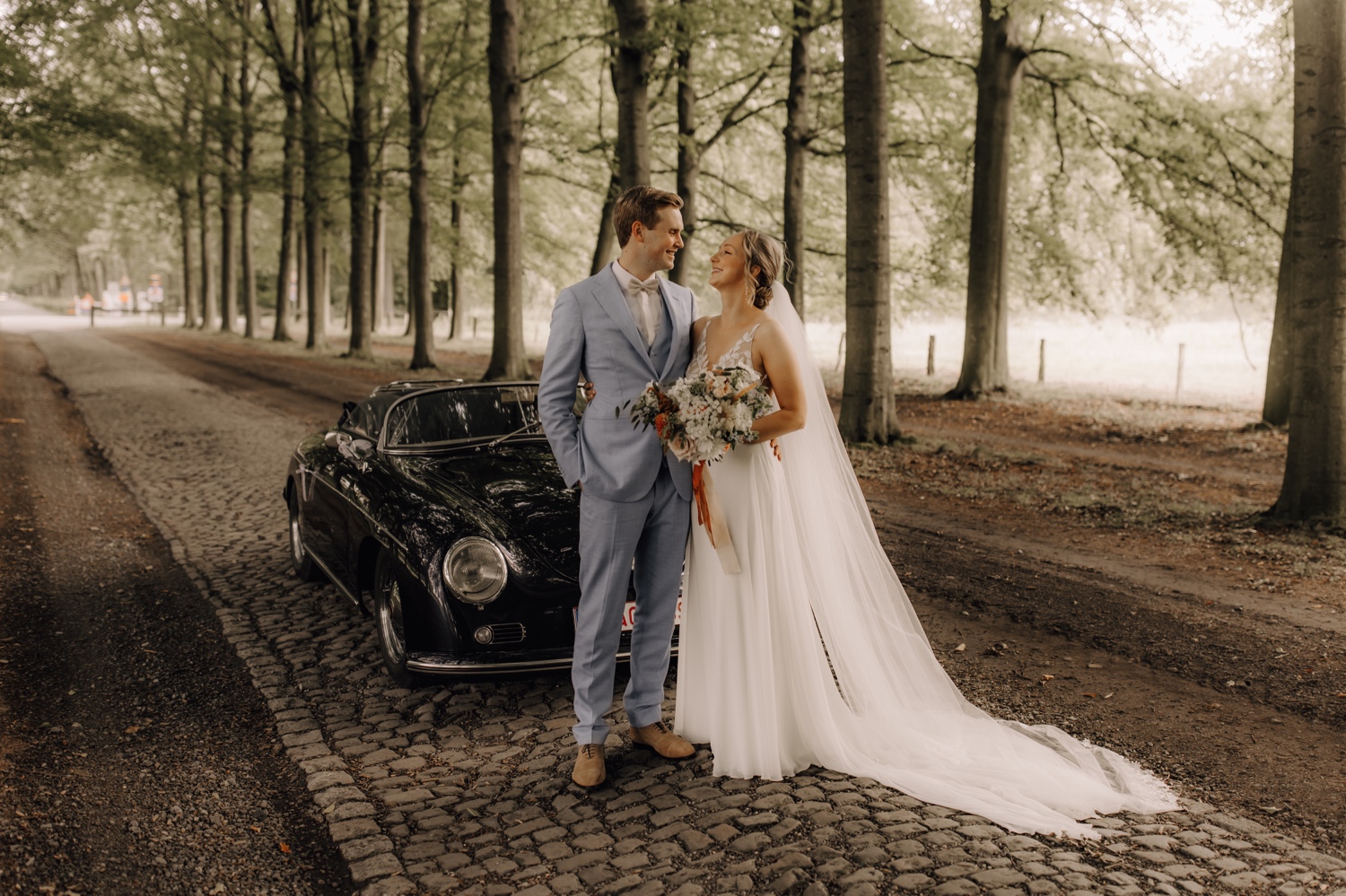 bruidspaar poseert voor hun oldtimer Porsche