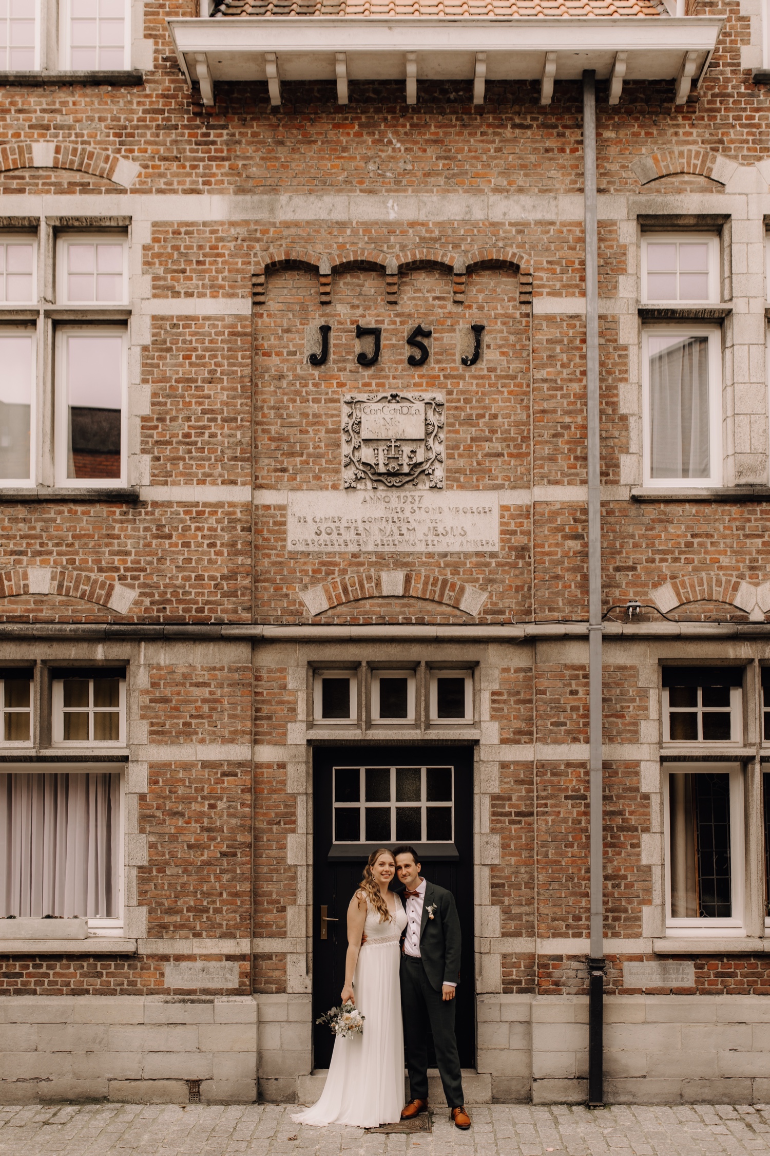 Huwelijksfotograaf Limburg - bruidspaar poseert voor stadswoning in Lokeren