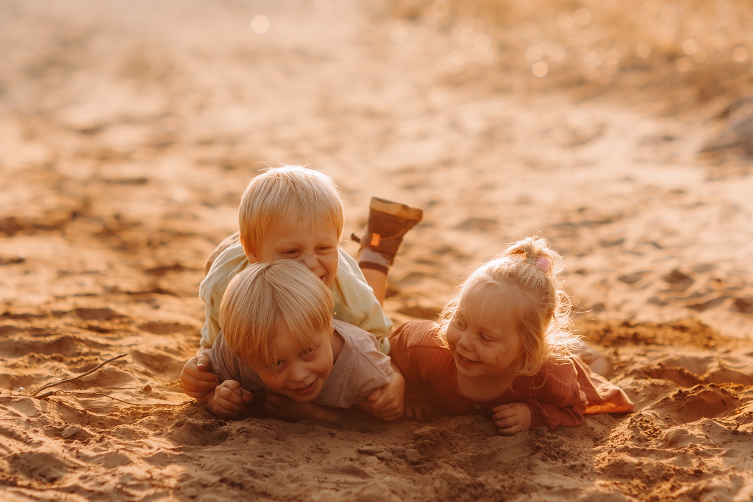 twee broertjes en hun zus rollen in het zand