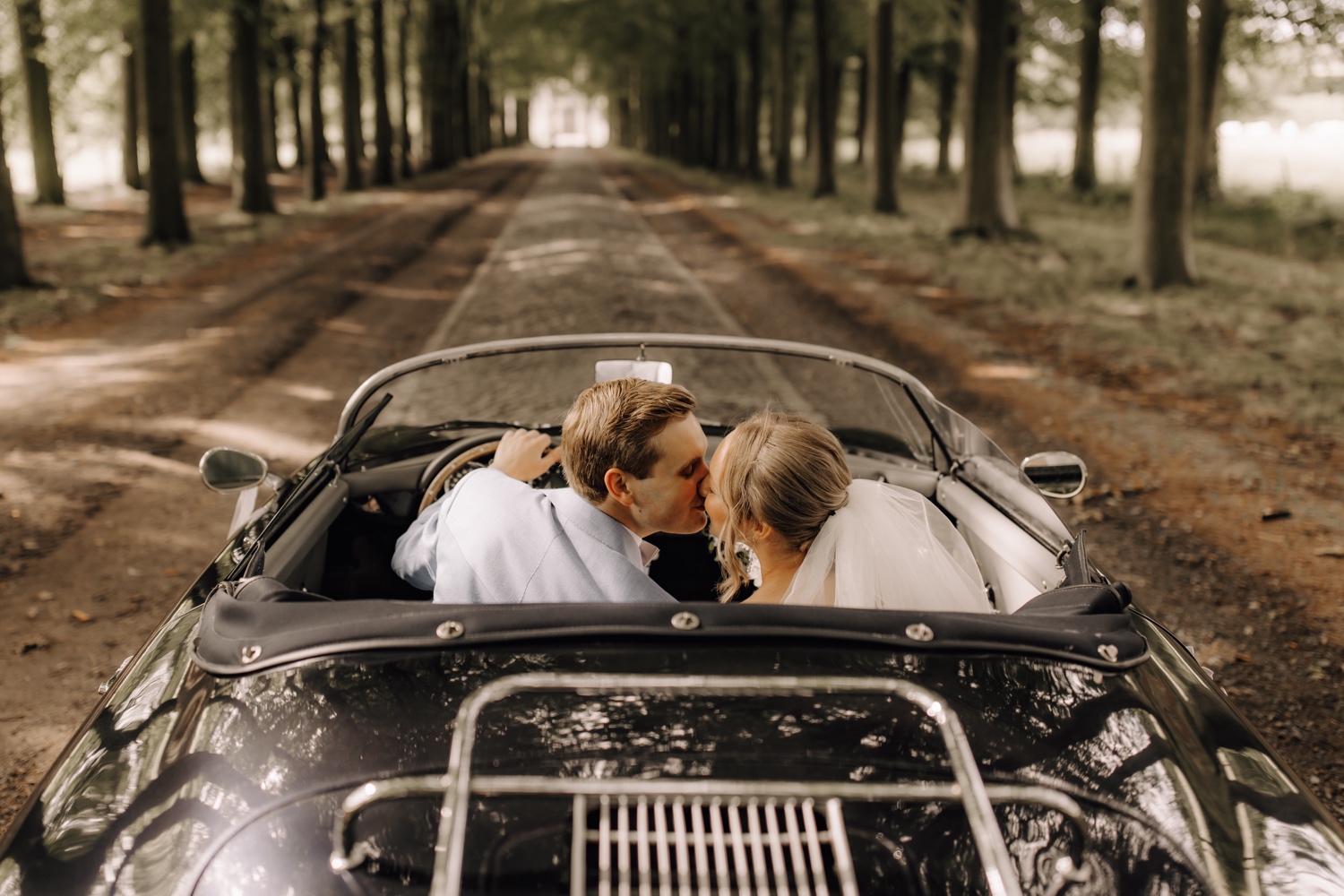 bruidspaar kust elkaar in de oldtimer Porsche