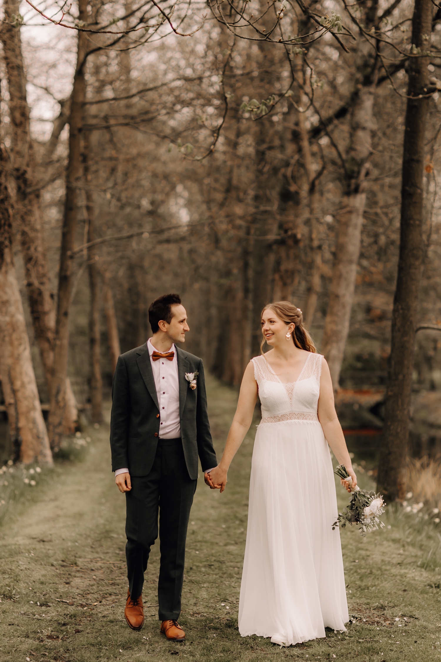 Huwelijksfotograaf Limburg - bruidspaar wandelt tussen de bomen