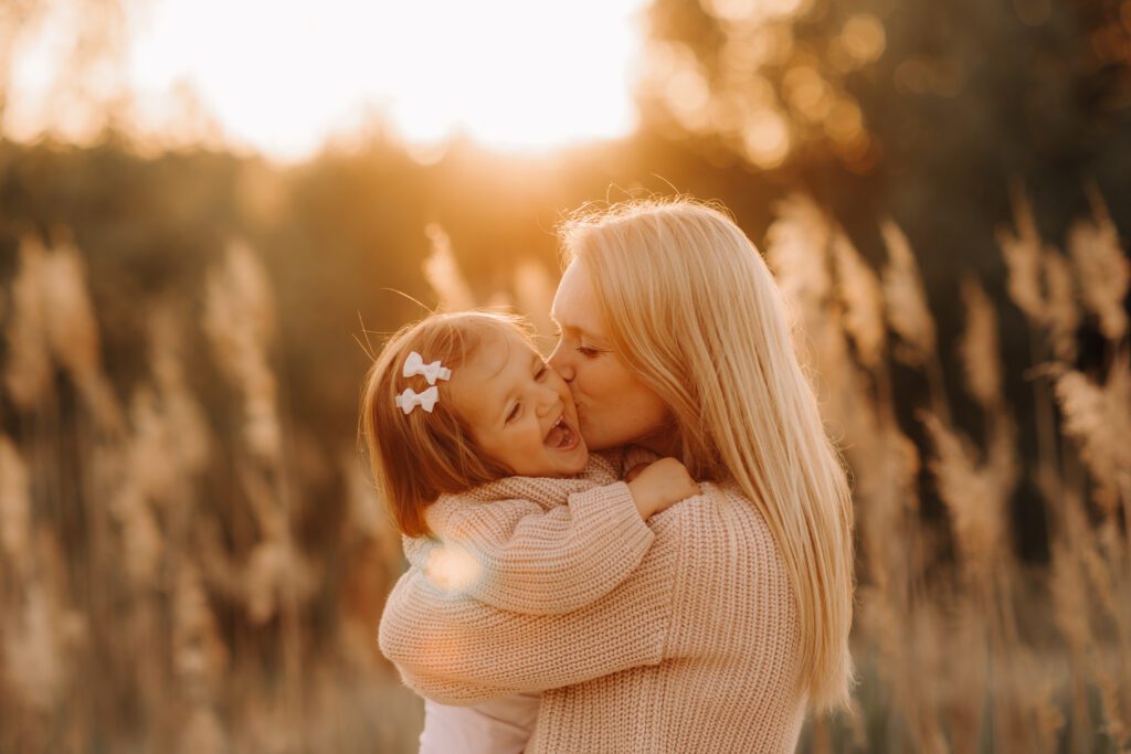 mama kust haar dochtertje op de wang tijdens zonsondergang