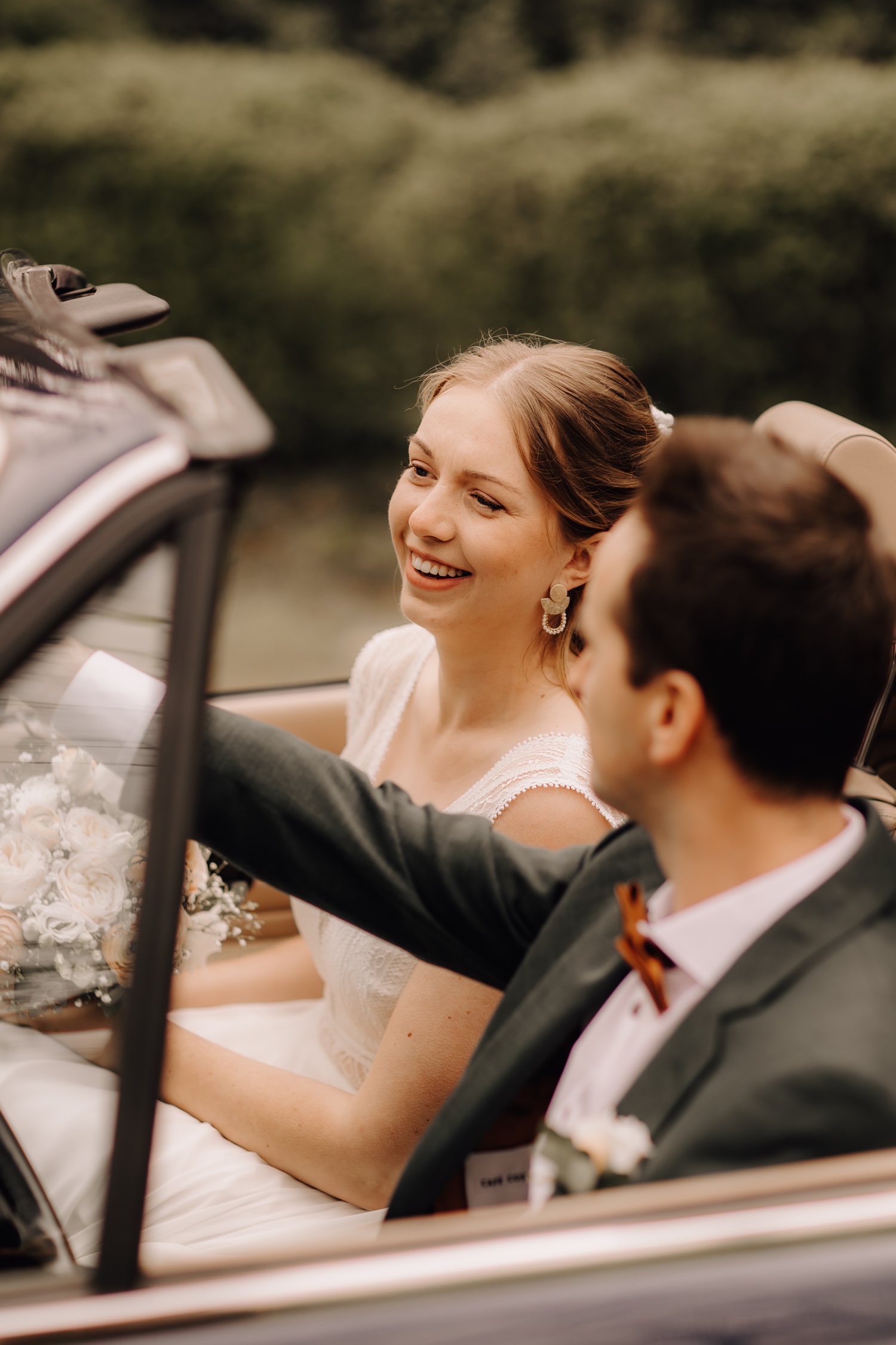 Huwelijksfotograaf Limburg - bruidspaar lacht in bruidswagen