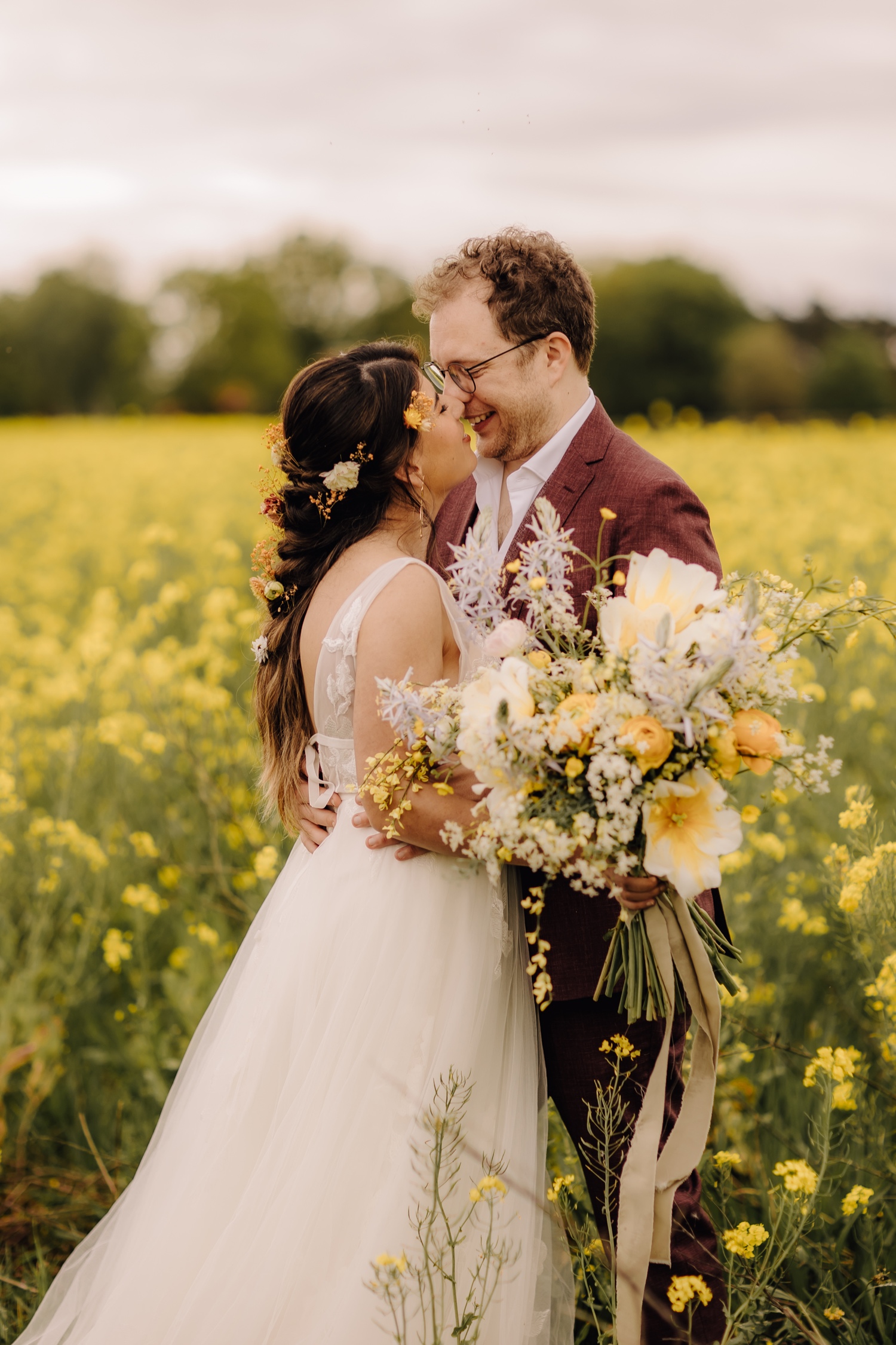 Huwelijksfotograaf Limburg - bruidspaar poseert tussen koolzaadbloemen