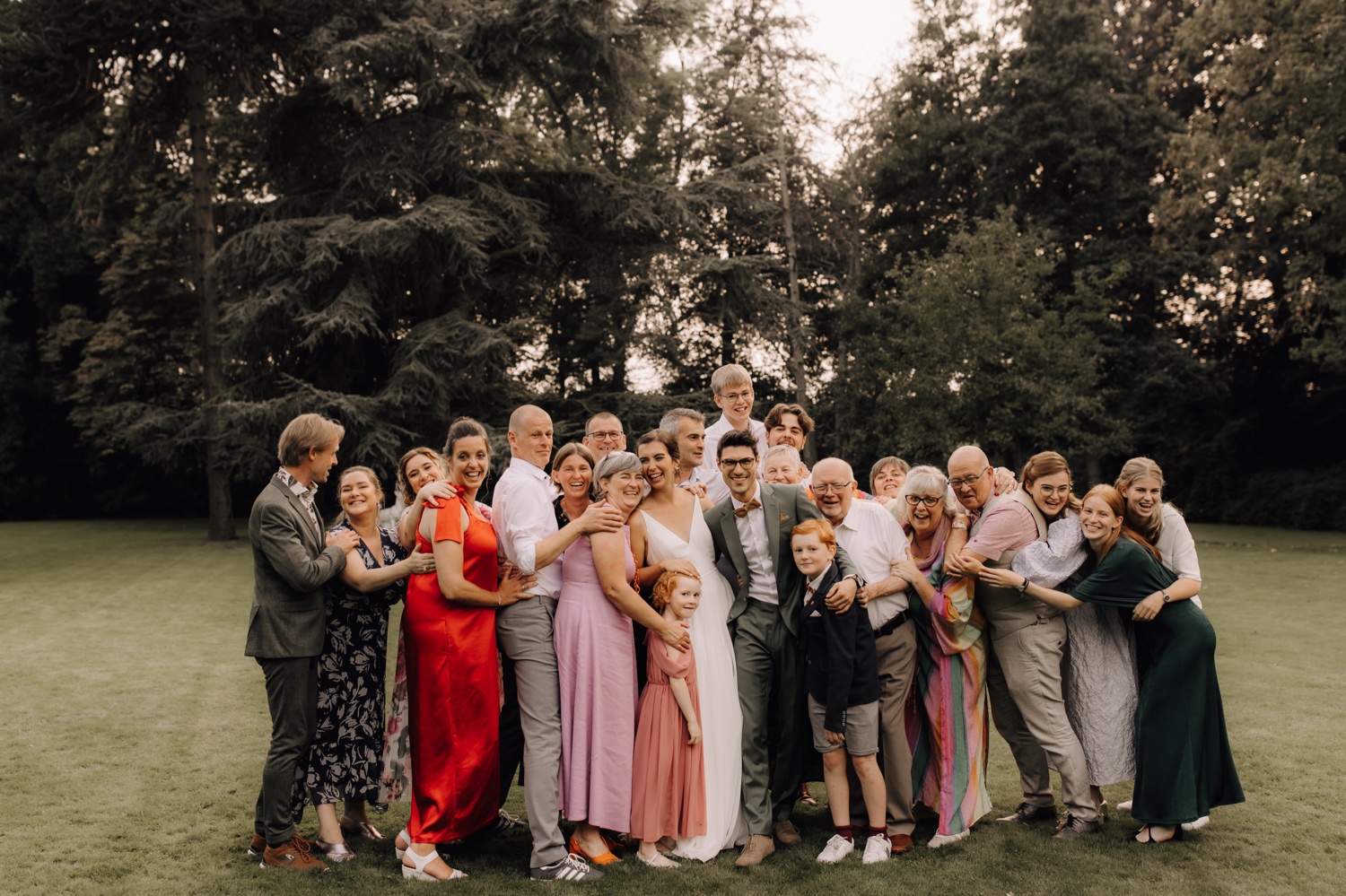 familie knuffelt bruidspaar in grote groep