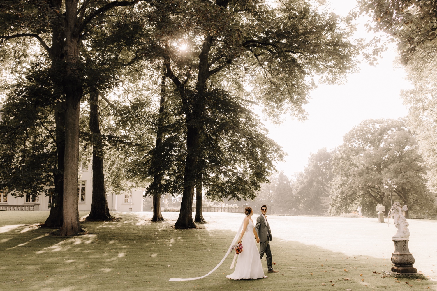 bruidspaar wandelt in het zonlicht door de tuin van kasteel Battenbroek