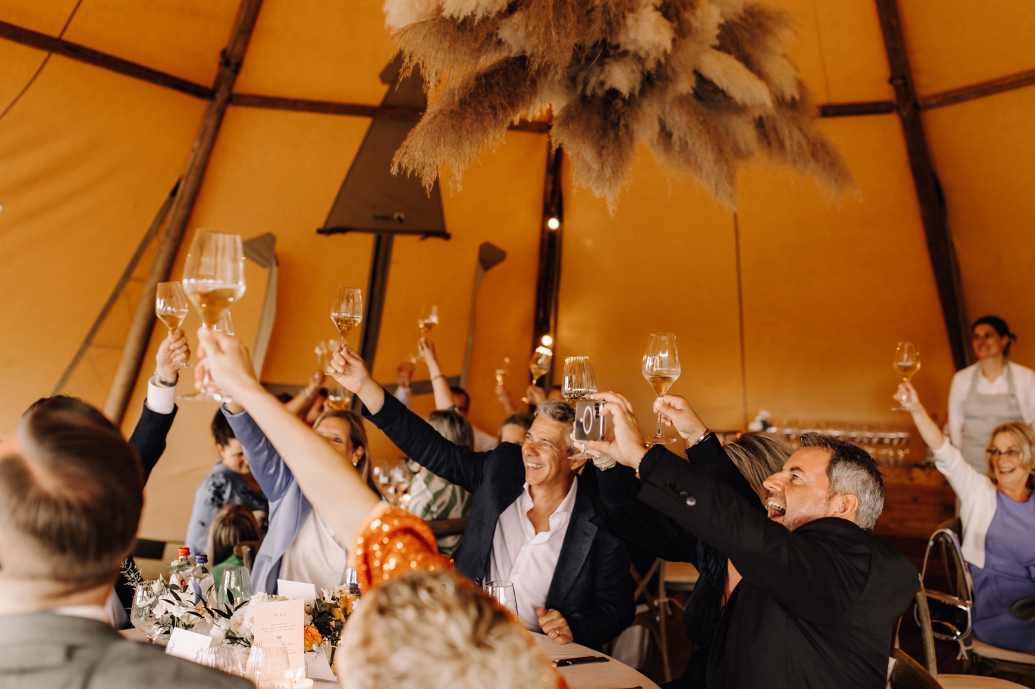 gasten klinken op het bruidspaar met hun wijnglas in de lucht