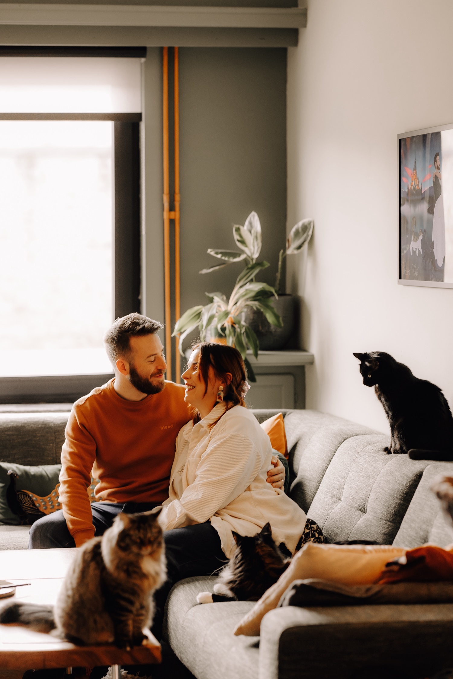 Gezinsfotograaf Limburg - koppel poseert met hun drie katten voor de thuisdier fotosessies in hun huiskamer