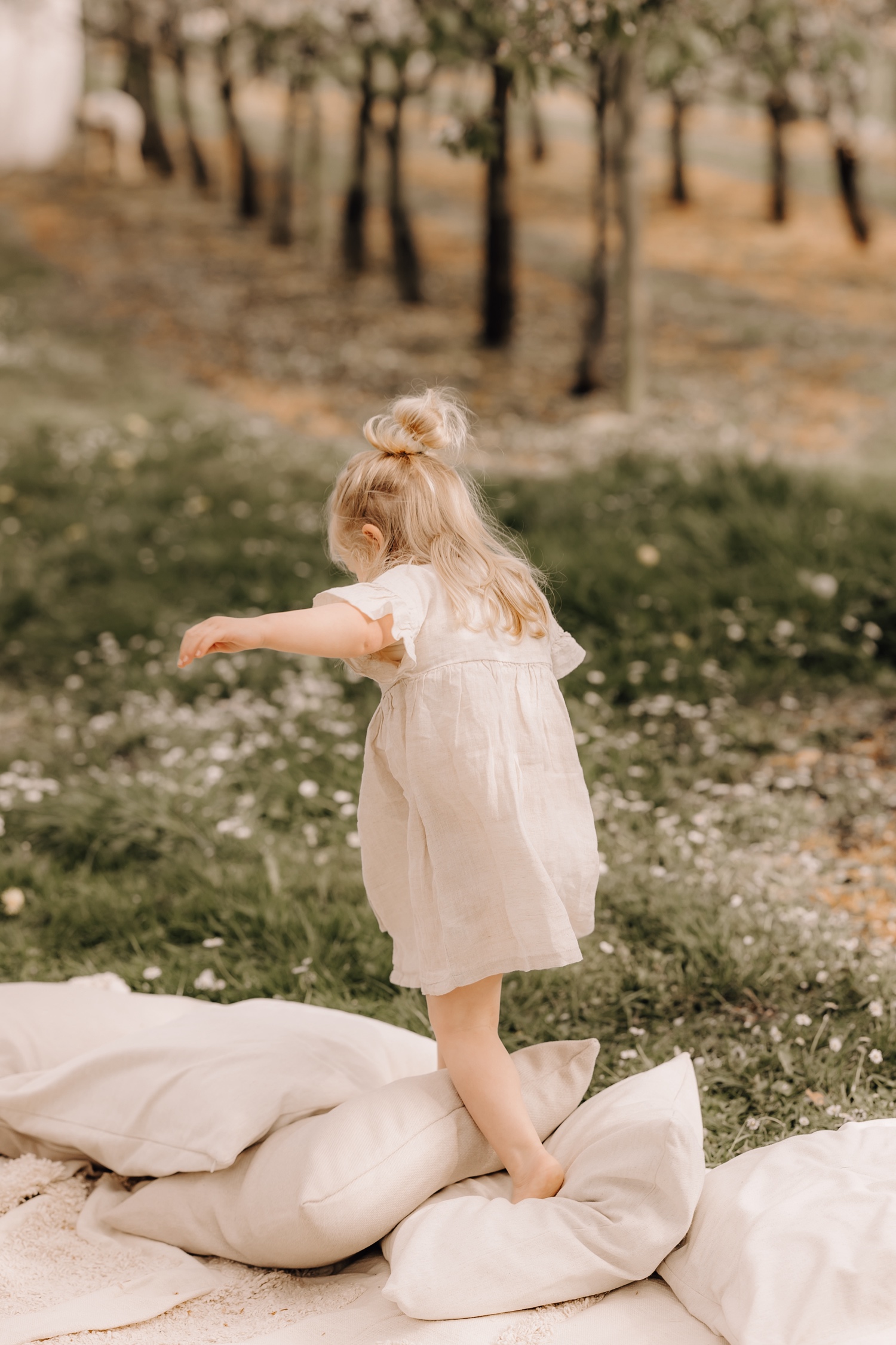 Gezinsfotograaf Limburg - dochtertje springt op kussens tussen de bloesems