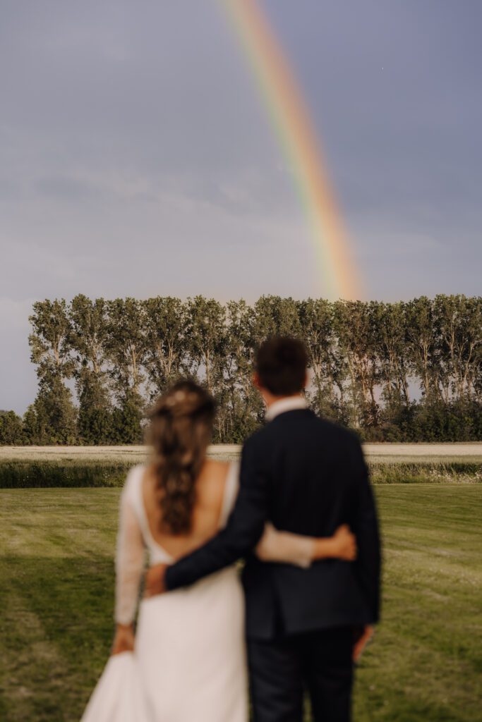 Huwelijksfotograaf West-Vlaanderen - bruidspaar kijkt naar regenboog aan Hoeve Engelendael