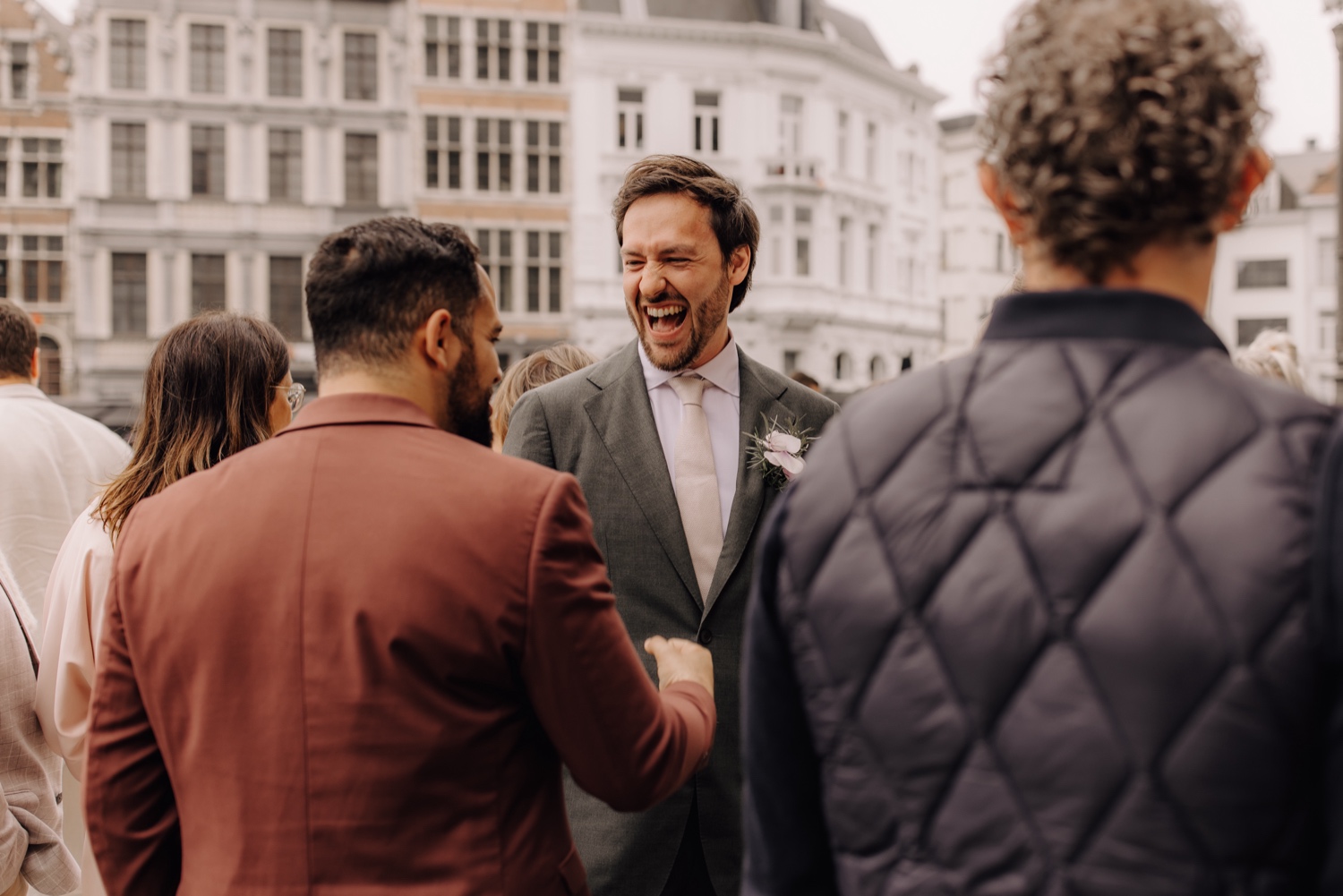 Huwelijksfotograaf Antwerpen - bruidegom lacht voor het stadhuis van Antwerpen