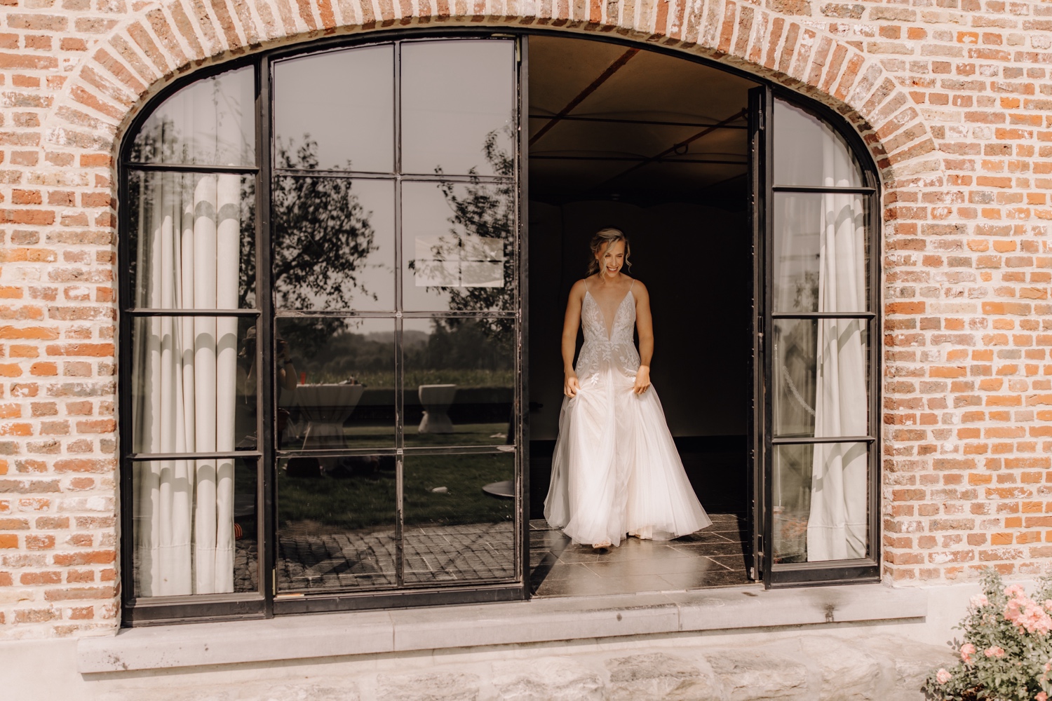 Zomers huwelijk op unieke landelijke locatie in Horebeke - bruid wandelt richting bruidegom voor hun first look in de tuin