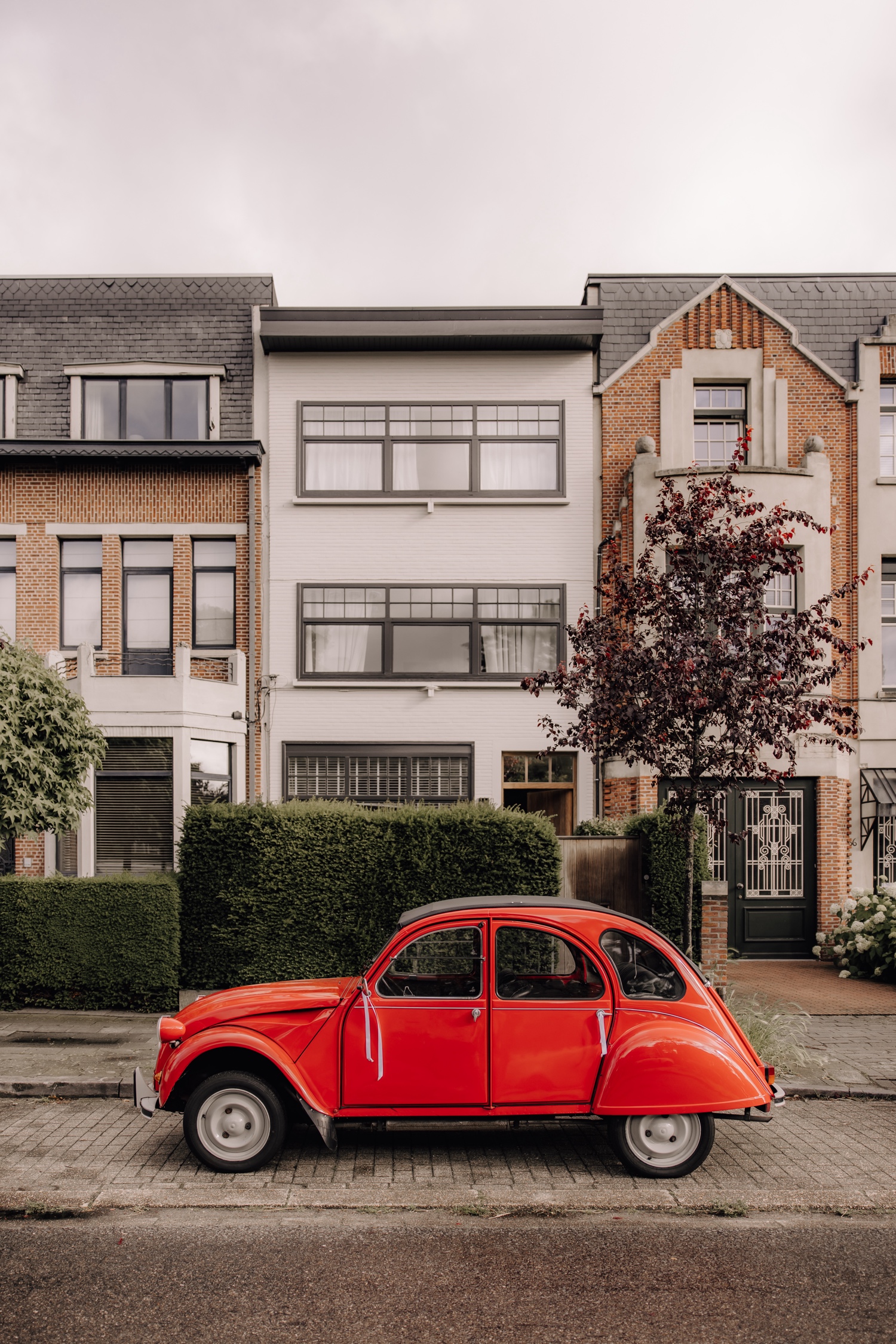 Een regenachtige huwelijksdag bij Hoeve Engelendael - foto van de knalrode oldtimer voor het huis van het bruidspaar