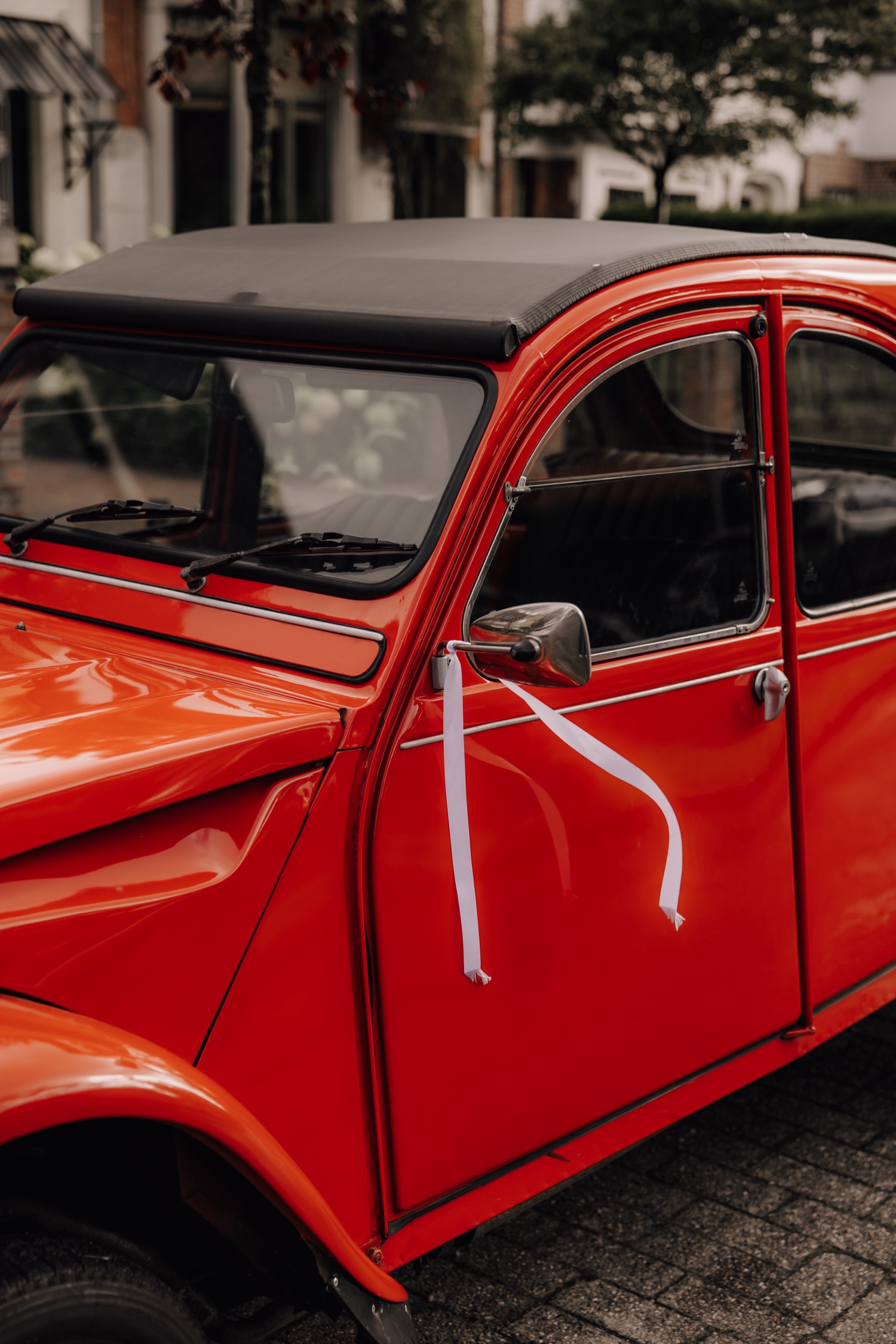 Een regenachtige huwelijksdag bij Hoeve Engelendael - close-up van een lintje aan de spiegel van de oldtimer